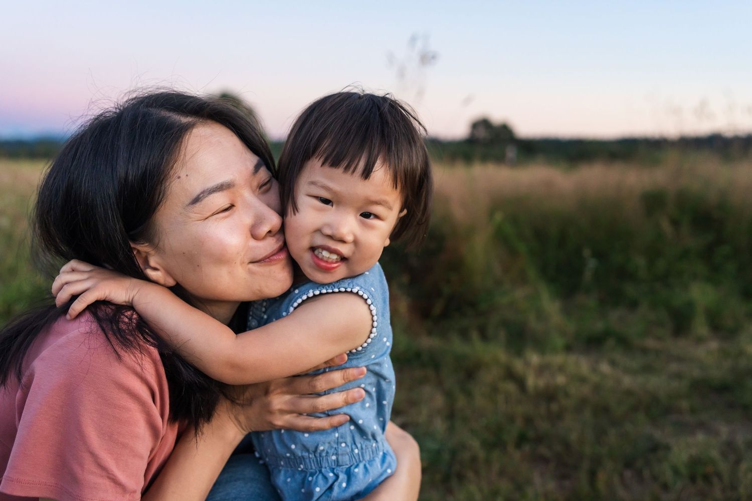 Mom hugging her daughter in a grassy field at blue hour in Marymoor Park.
