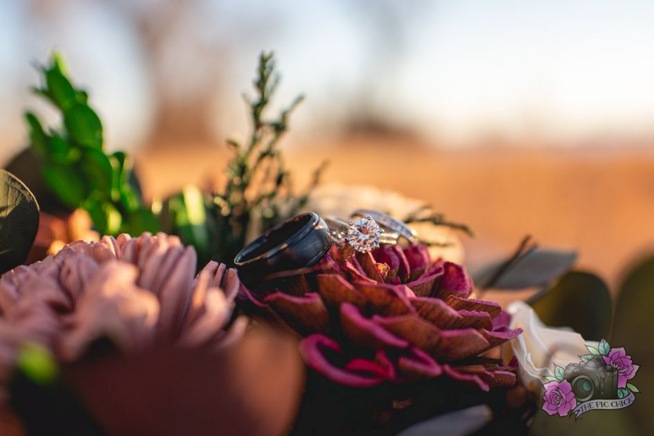 A macro shot of deep pink and burgundy wedding flowers with greenery in soft focus.