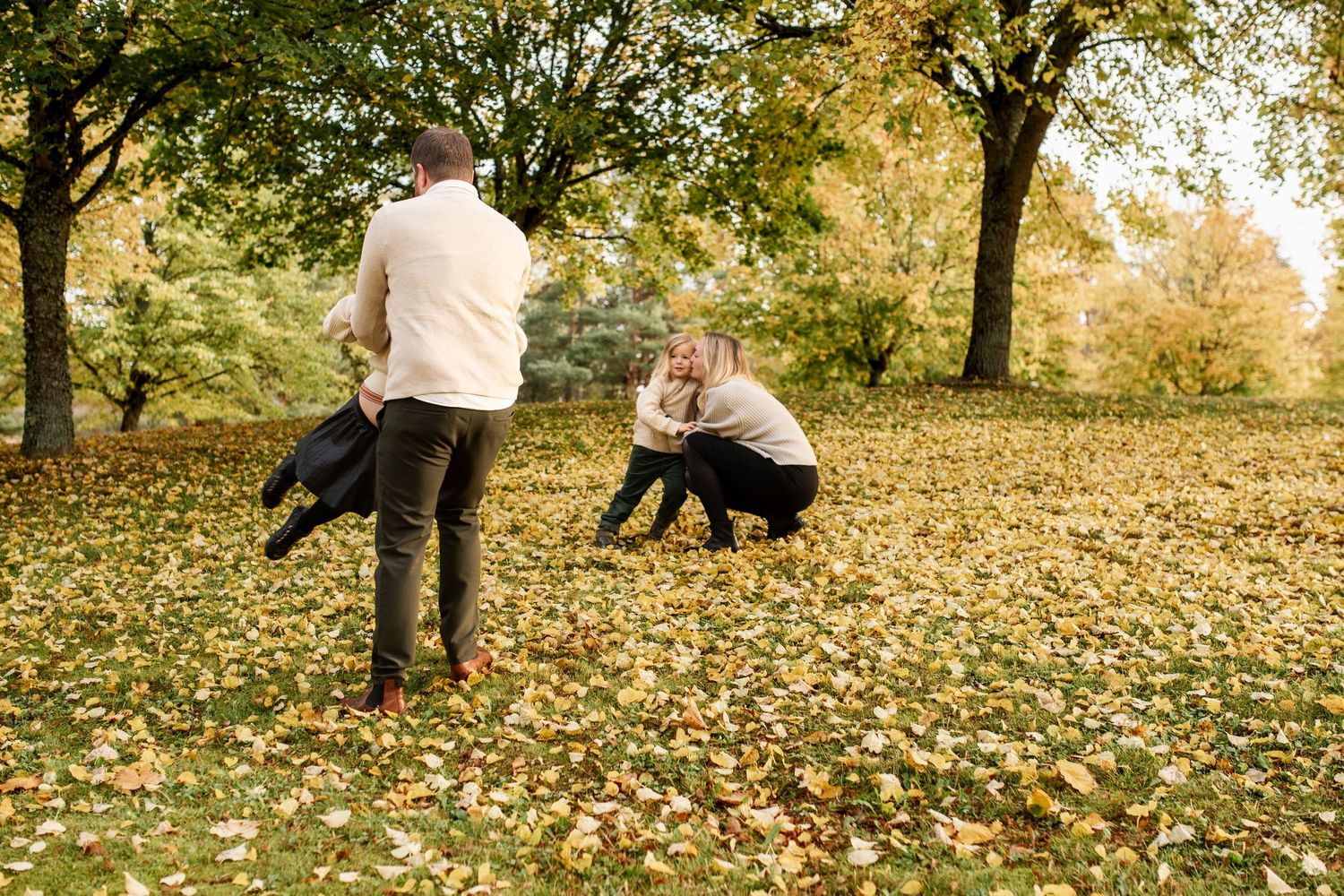 People playing in fallen autumn leaves on a golden afternoon in the park.