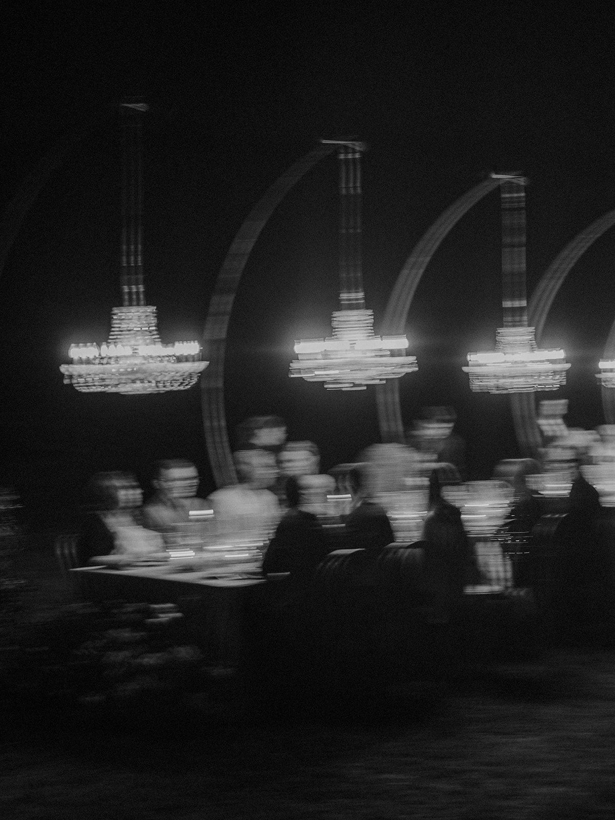 Blurred motion capture of chandeliers and guests at an elegant evening event.