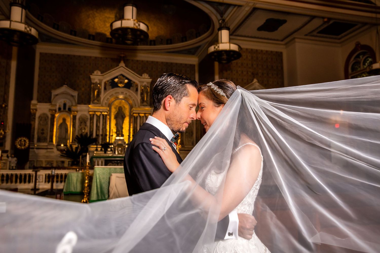 Elegant wedding ceremony in a church with soft lighting and flowing white veil.