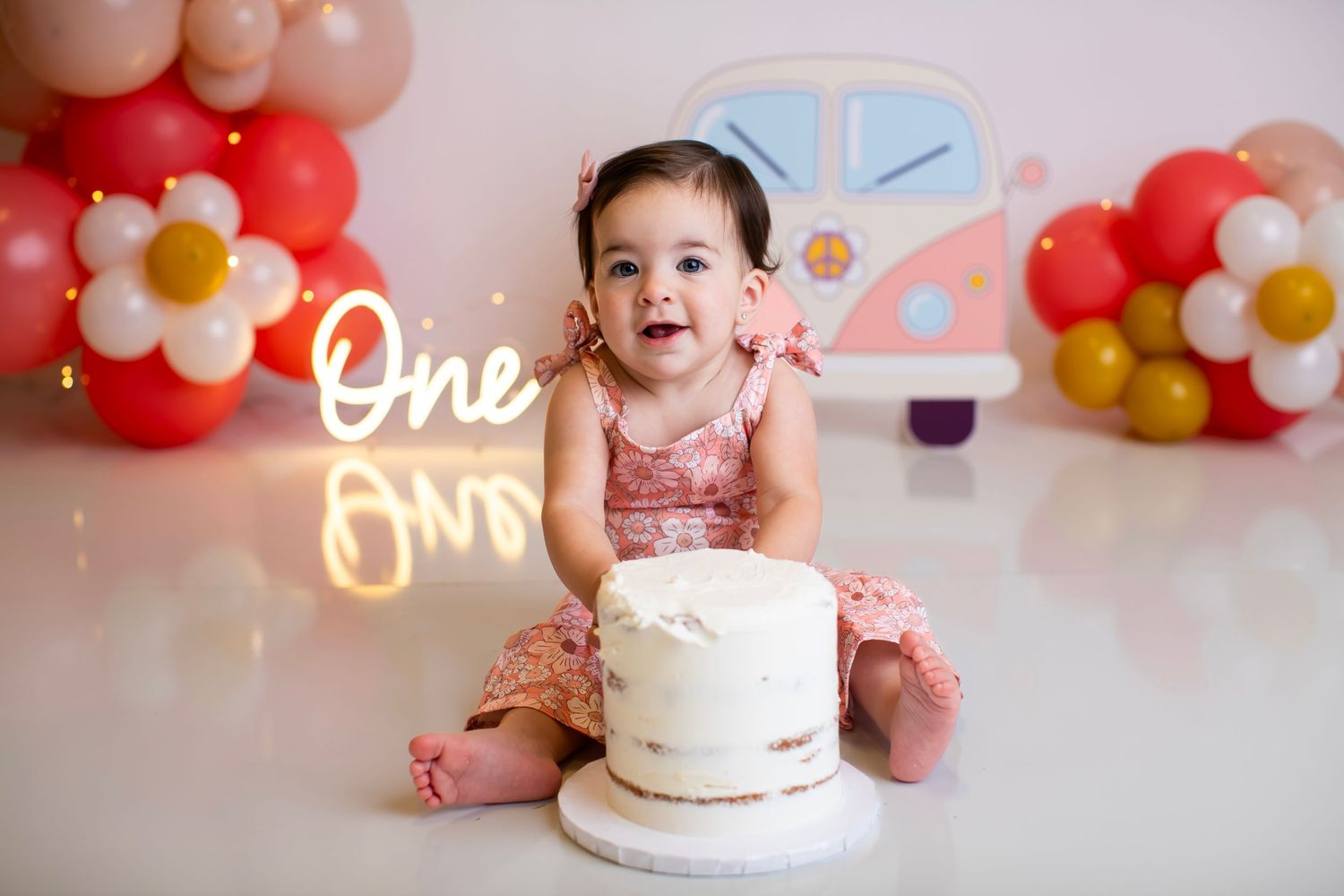 First birthday celebration setup with cake, floral balloons and car themed decorations.