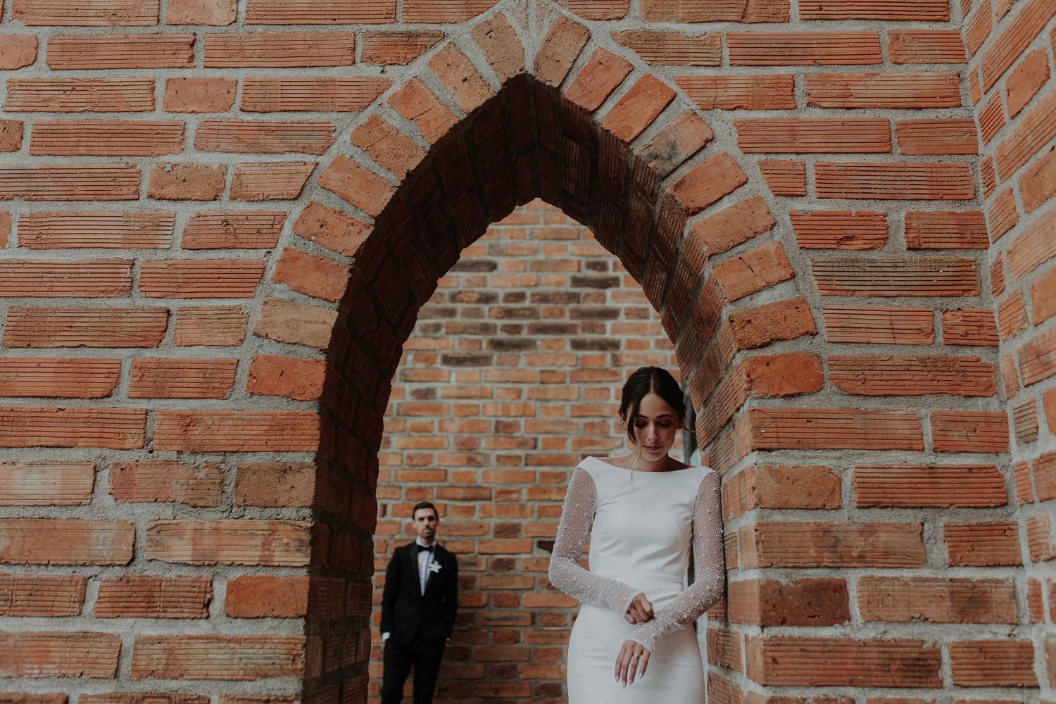 A dramatic architectural wedding photo featuring an arched brick doorway.
