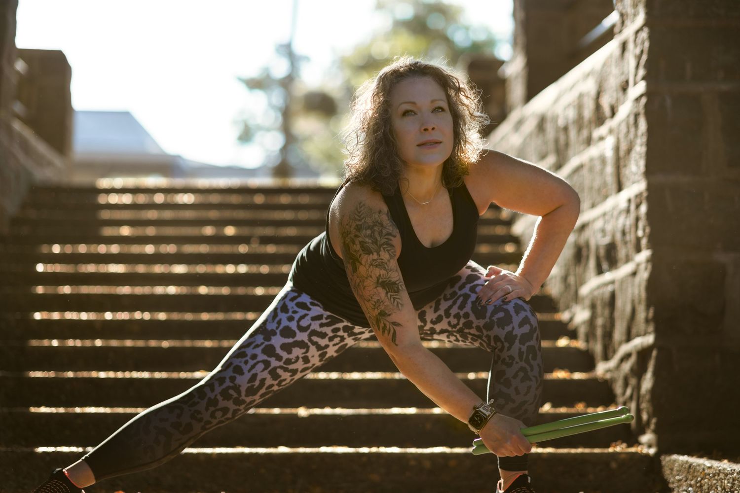 Fitness Instructor stretching on concrete stairway holding drumsticks