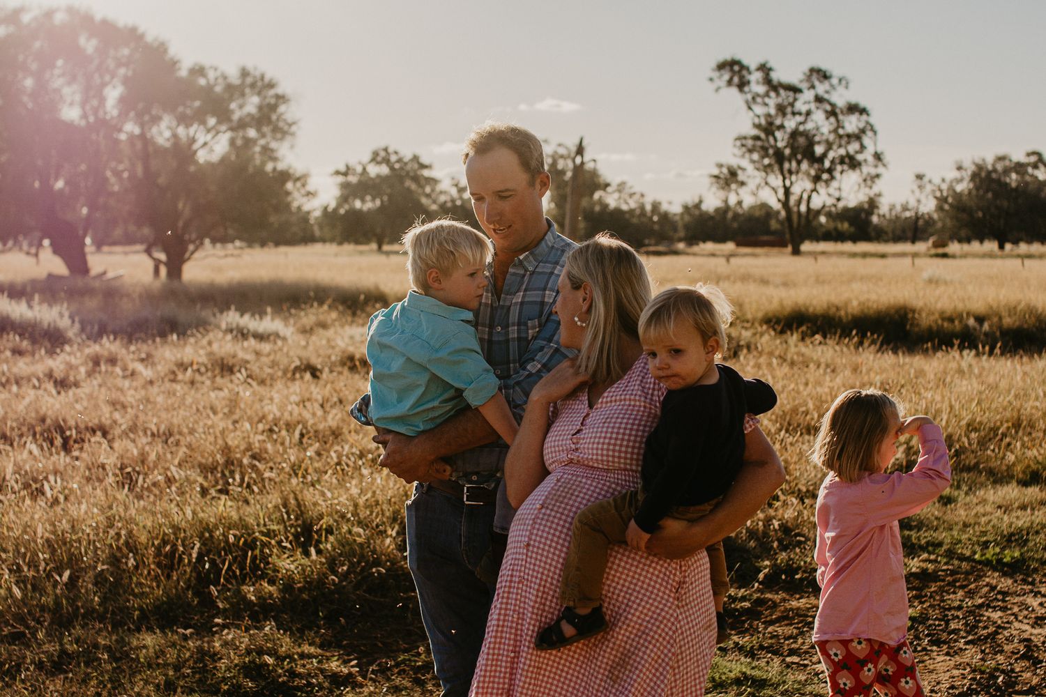 Rural family walking casual together in a paddock at golden hour