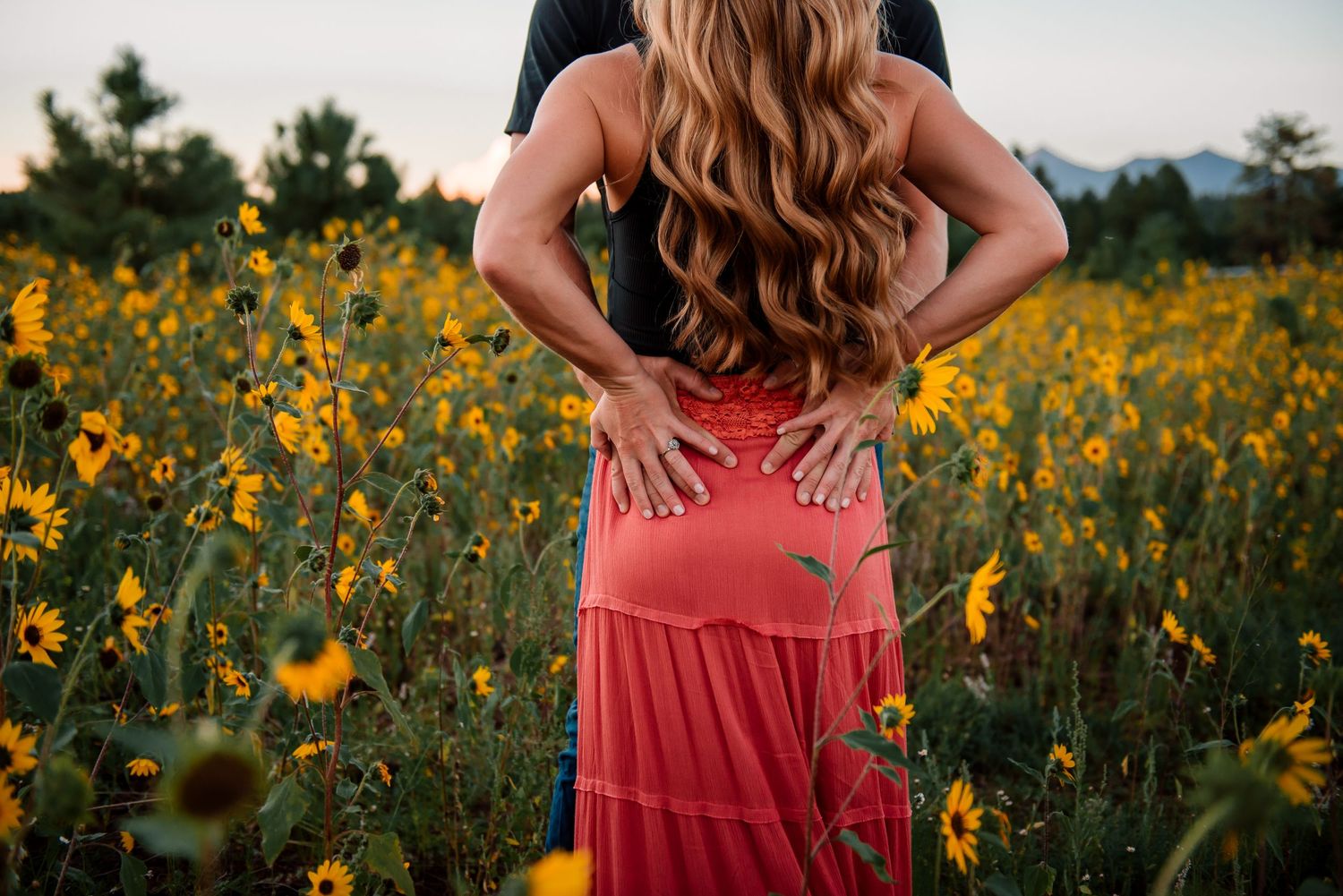 Close-up view of a coral tiered maxi skirt against a backdrop of yellow wildflowers.