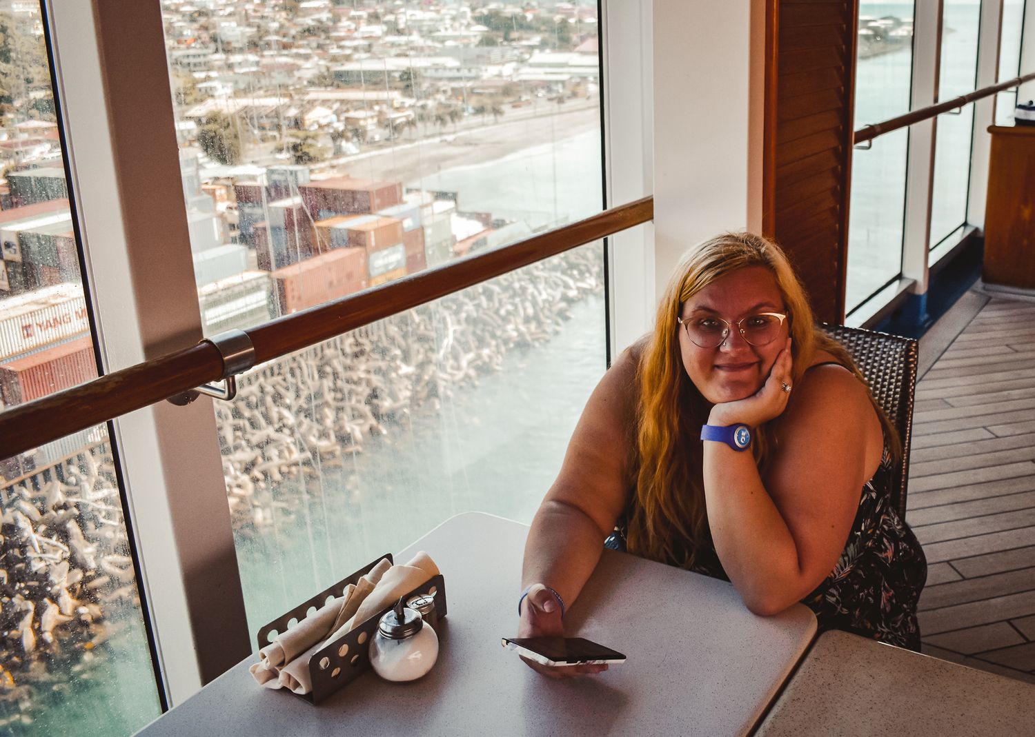 Person sitting at a window-side table with scenic city view in background.
