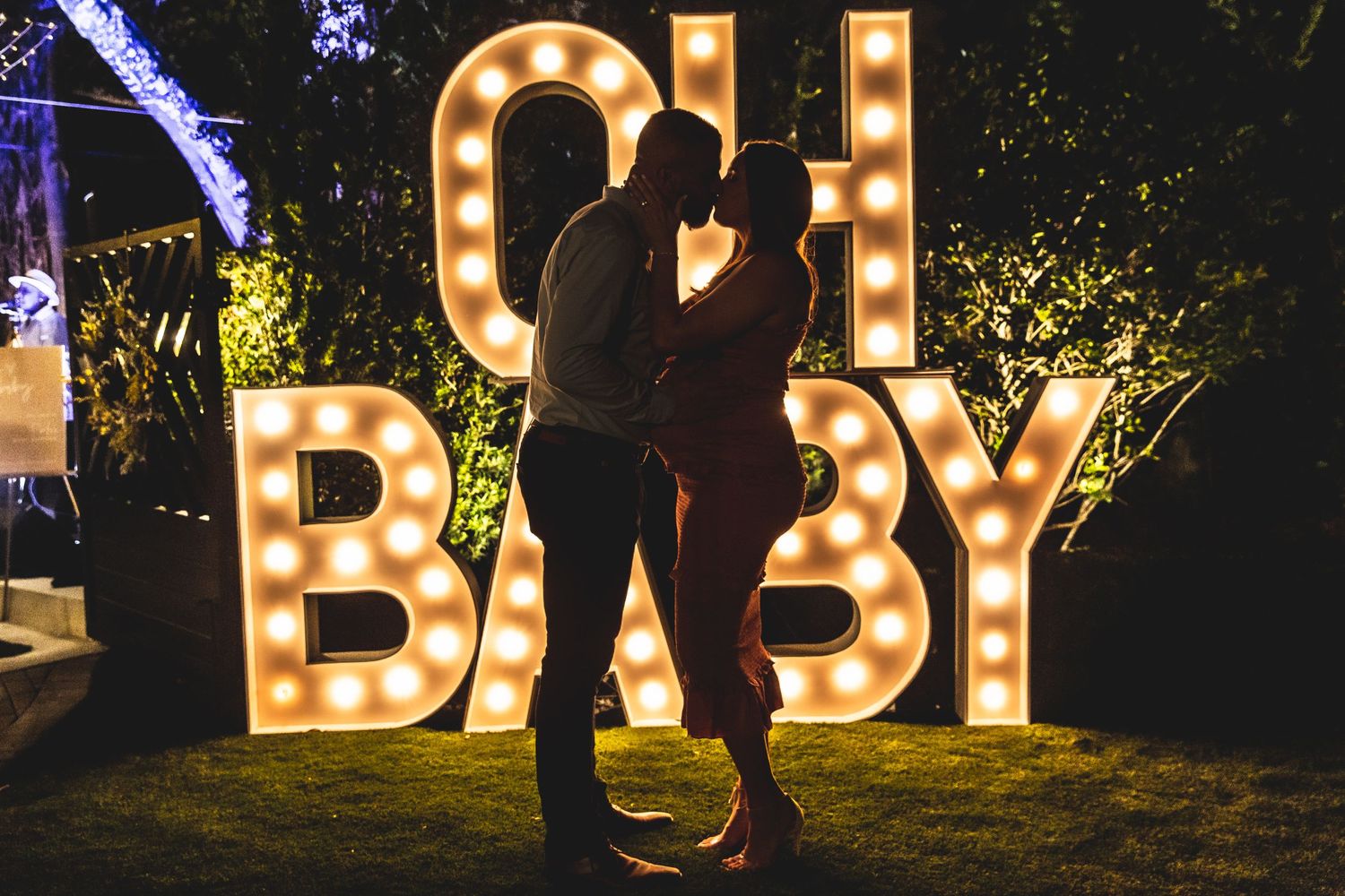 Decorative marquee letters spelling 'BABY' lit up against dark evening backdrop.