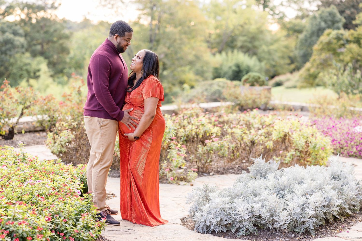 Couple standing in colorful garden during maternity photo session.