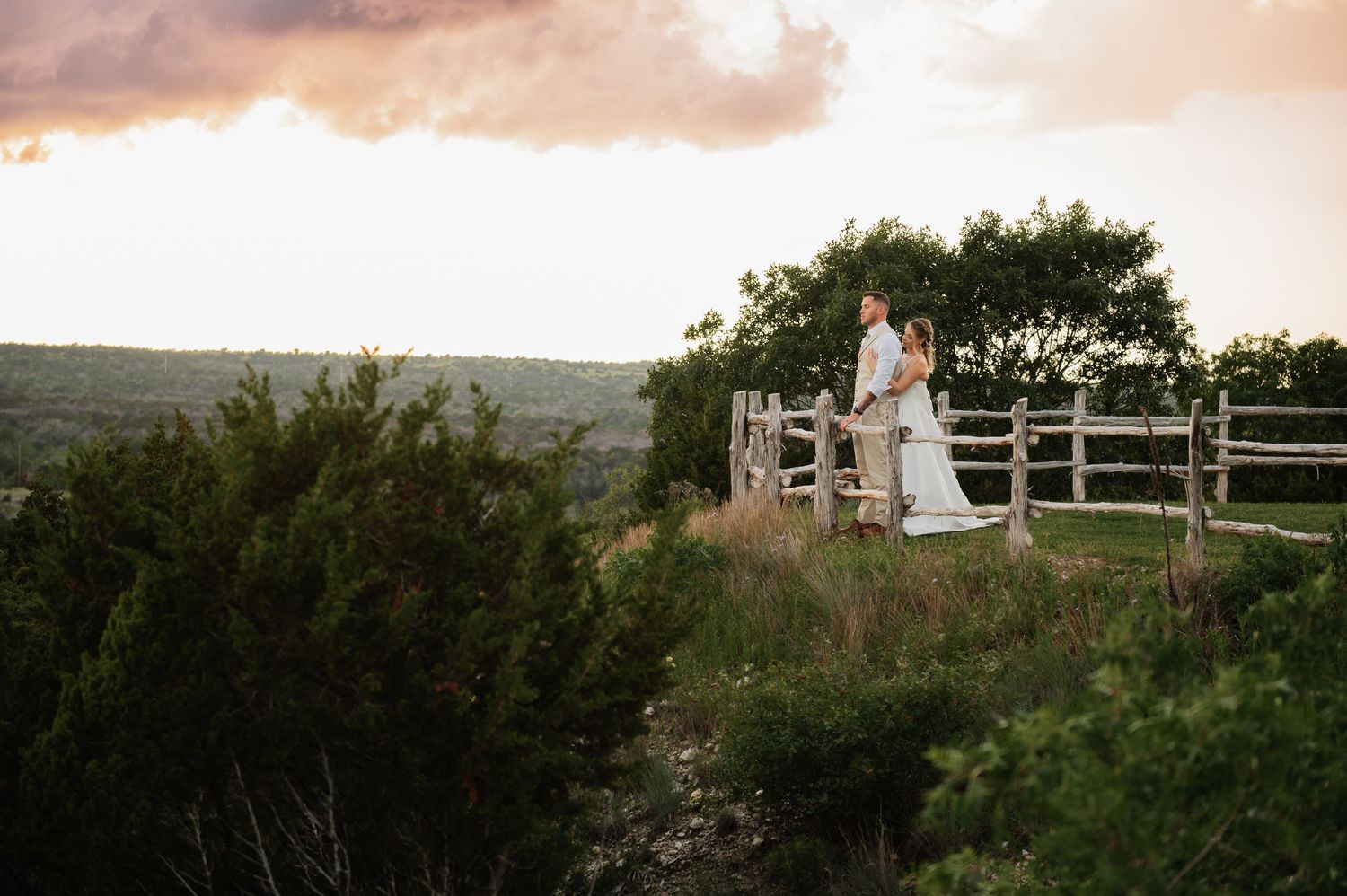 Bride and groom exchange vows at rustic indoor wedding ceremony with white chairs and floral arrangements.