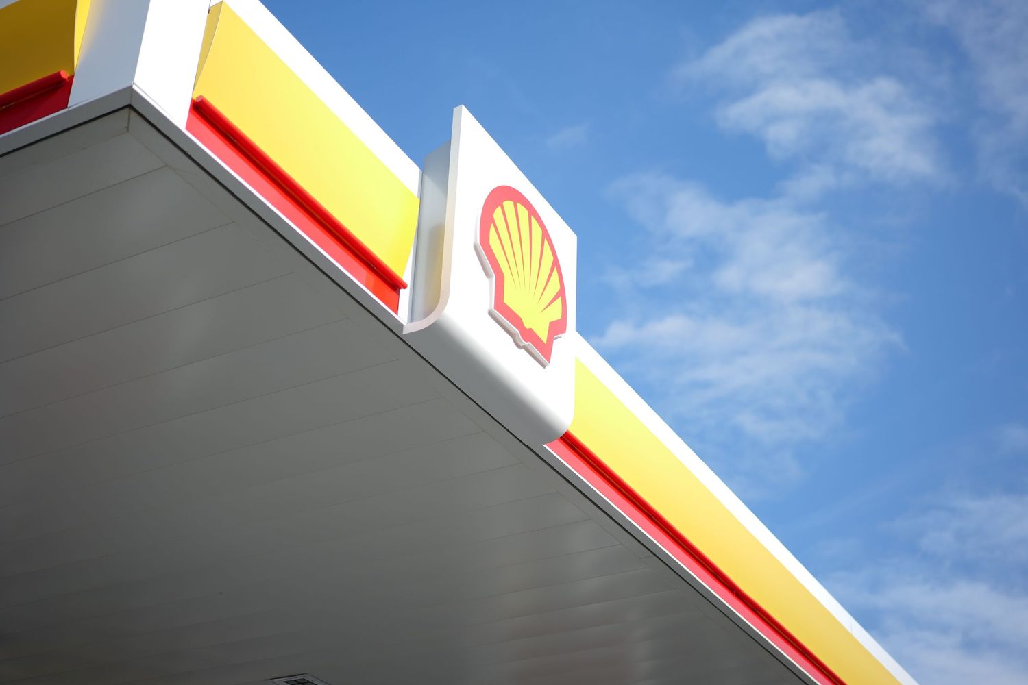 Shell gas station logo sign against a blue sky with yellow and red brand colors.
