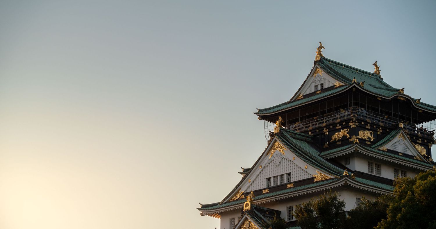 Japanese castle buildings with traditional architecture against blue sky.