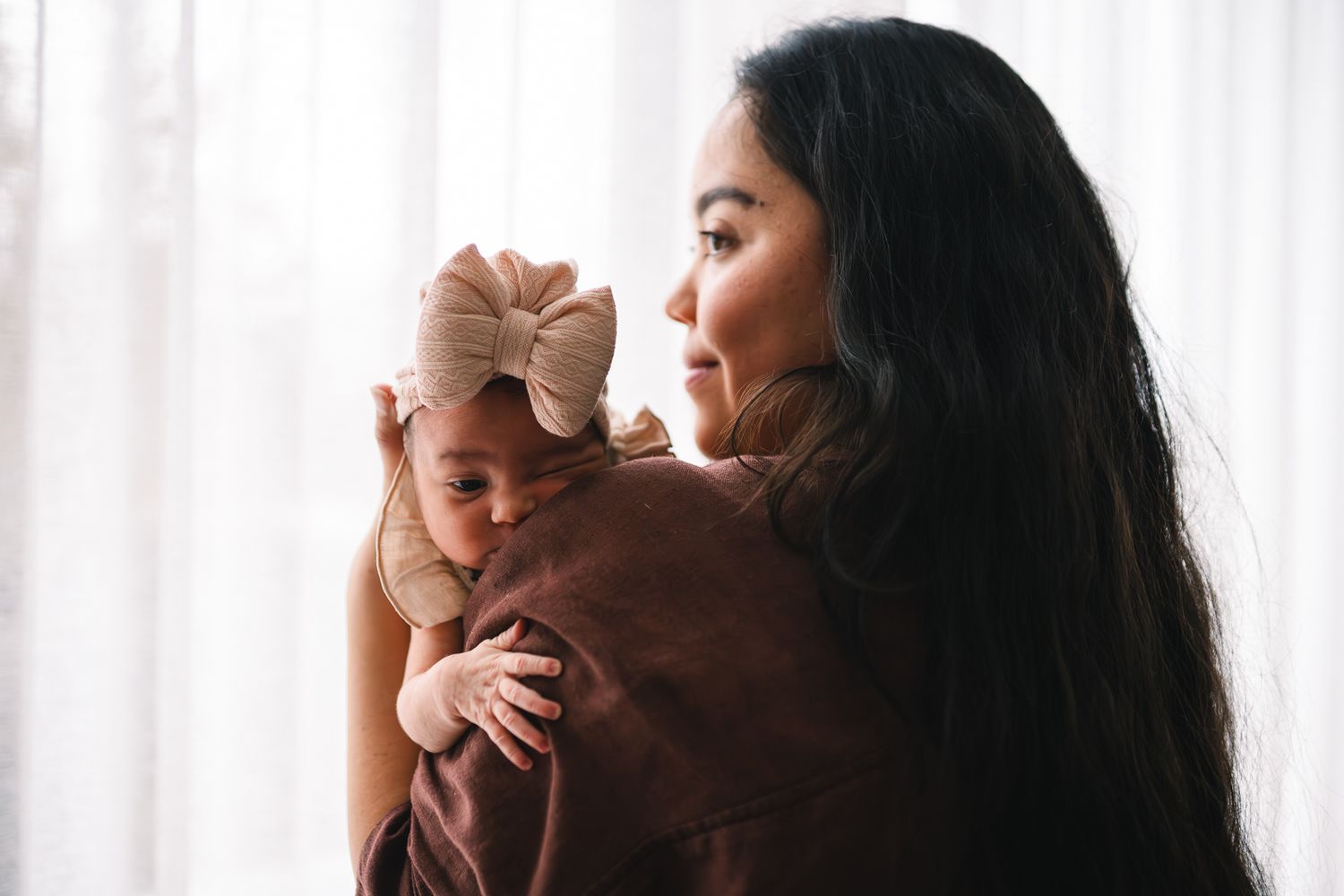 Mother cradling her newborn daughter during a newborn photoshoot at home by Melbourne newborn and family photographer Pei A Photography