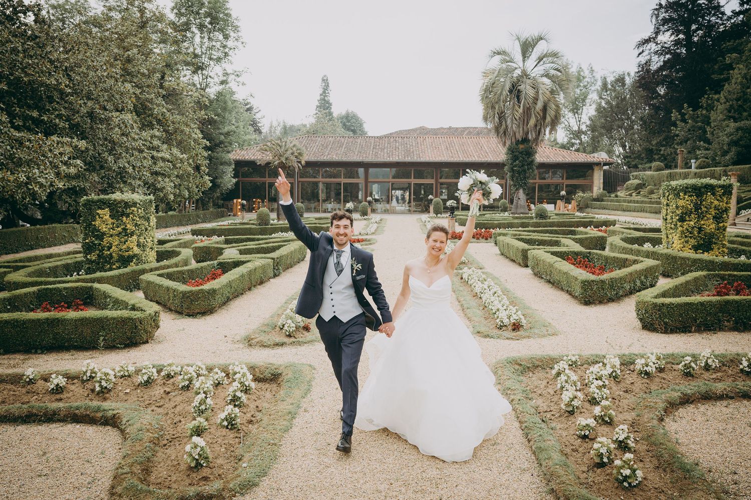 Novios caminando de la mano por los jardines del Palacio de Valdesoto al atardecer, durante su reportaje de boda en Asturias