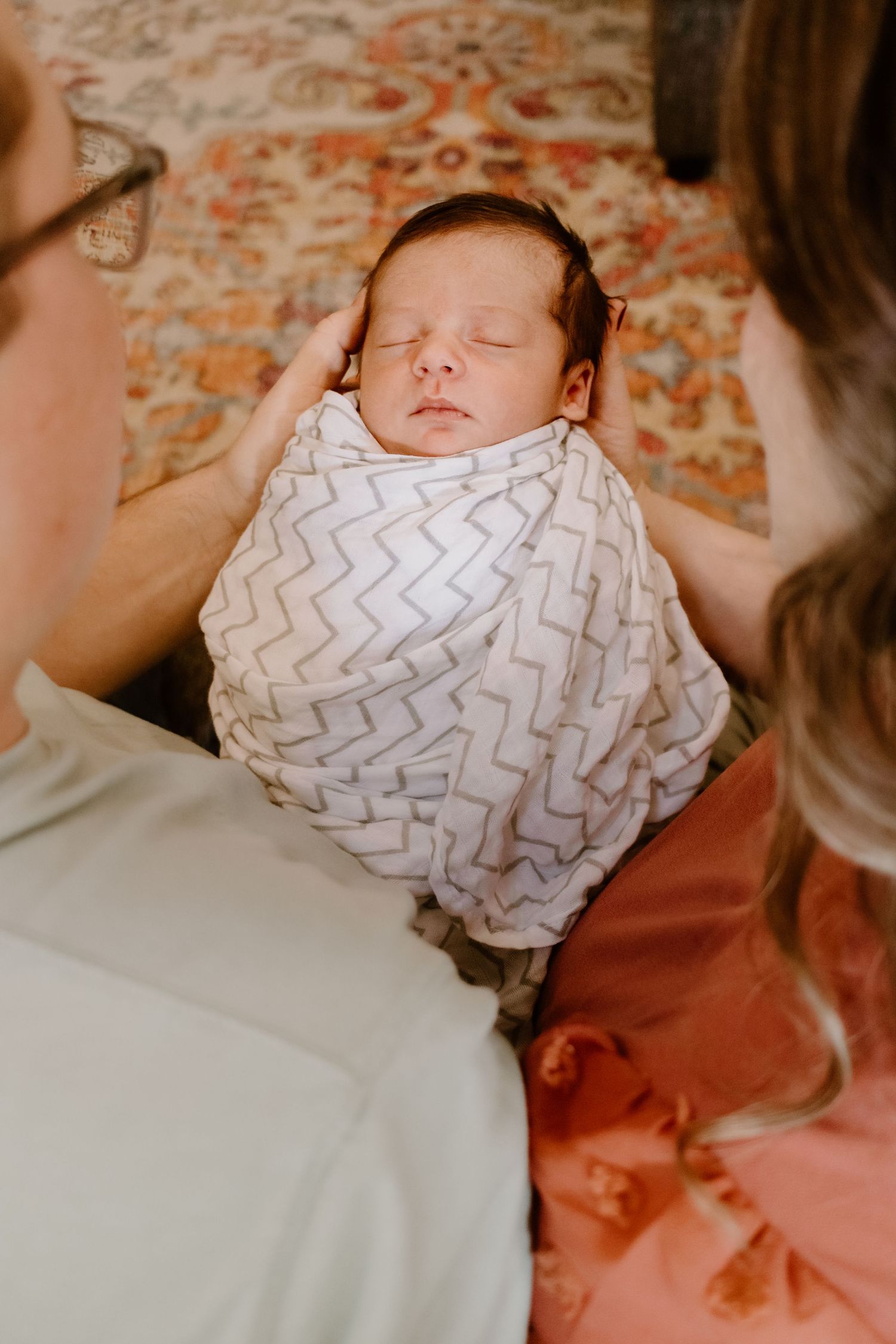 Newborn baby wrapped in chevron pattern blanket sleeping peacefully.