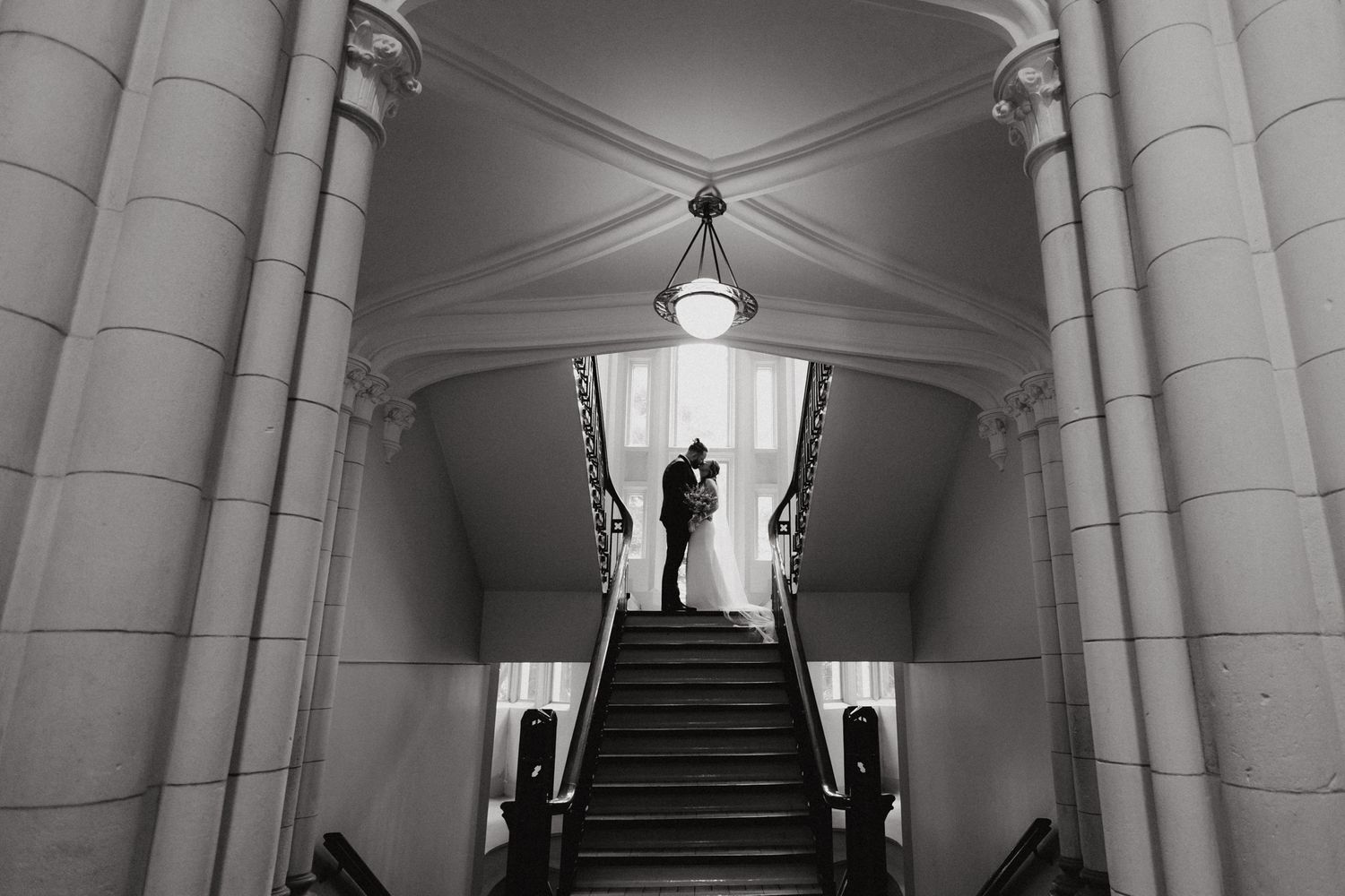 Romantic kiss by newly wed couple in a stunning architecture, captured by Apertured Media Auckland Wedding Photographer.