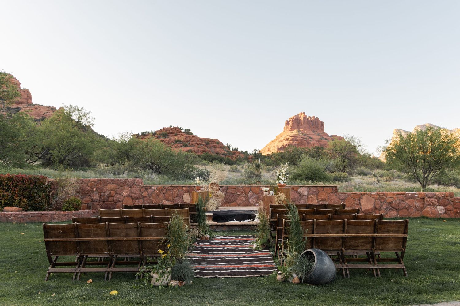 Rows of wooden benches face majestic red rock cliffs at sunset in Sedona, Arizona's natural amphitheater setting.