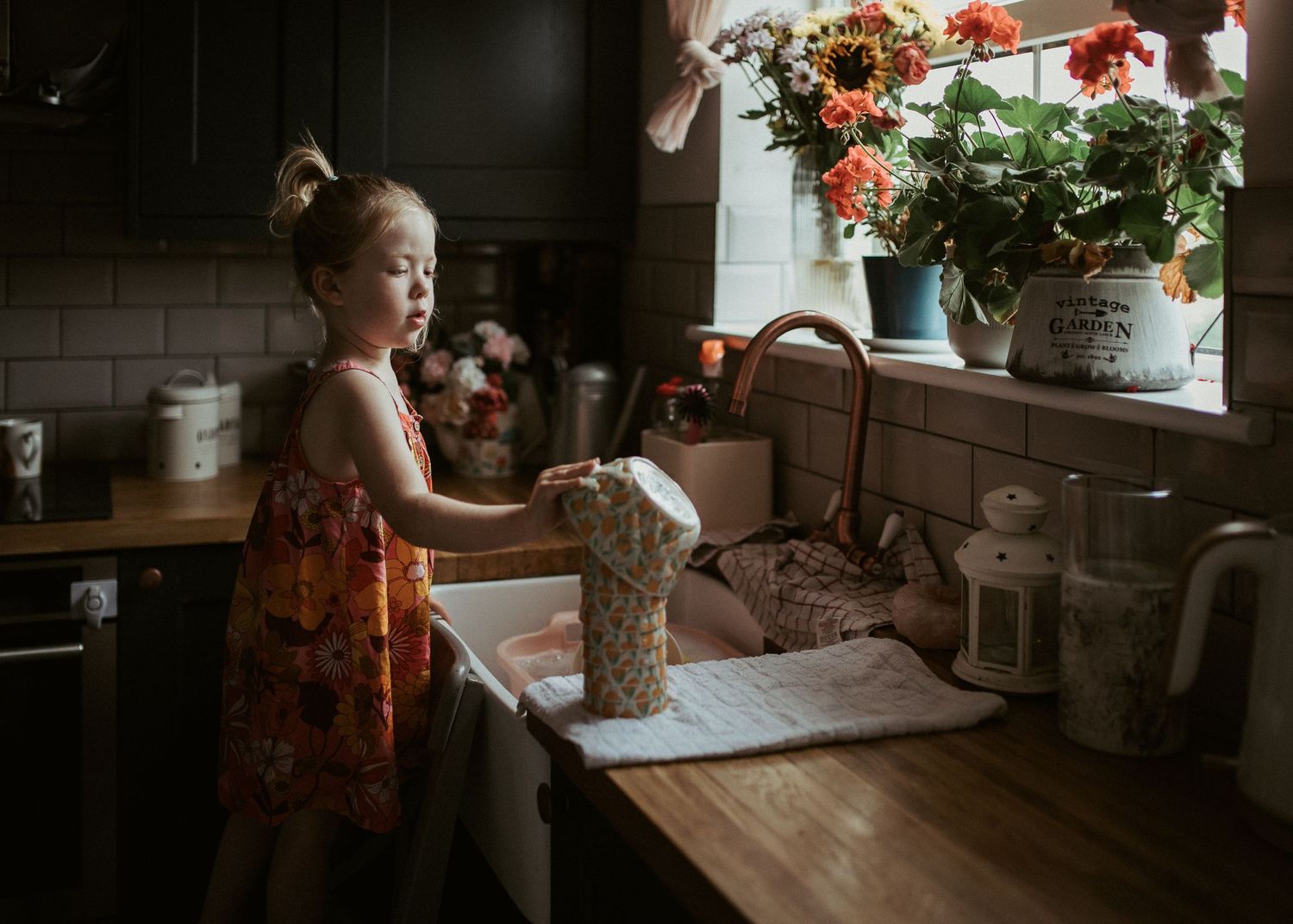 Candid lifestyle photo of girl washing dishes in natural window light