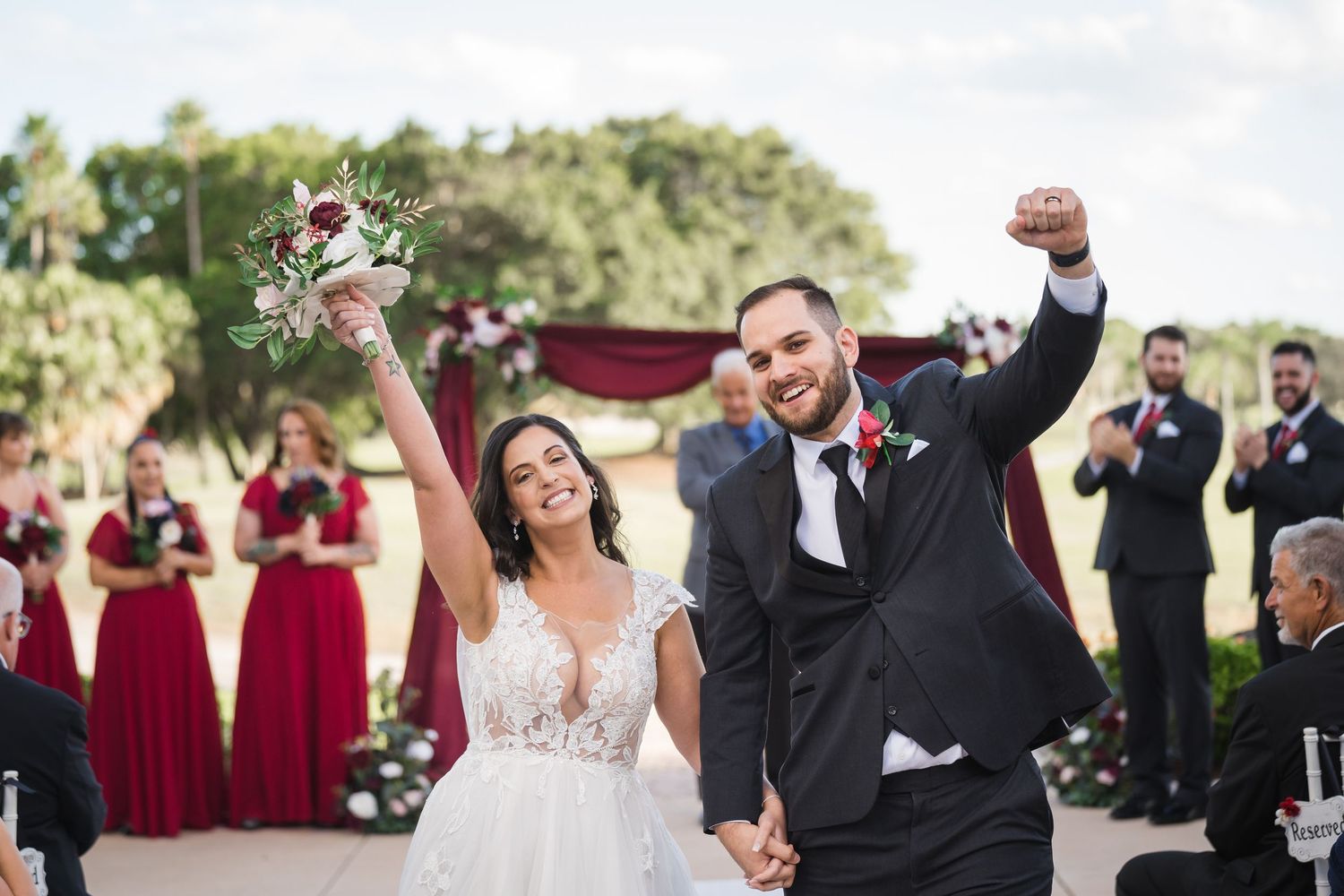 A tender moment between newlyweds embracing outdoors, with the bride in a lace white dress and groom in black suit.