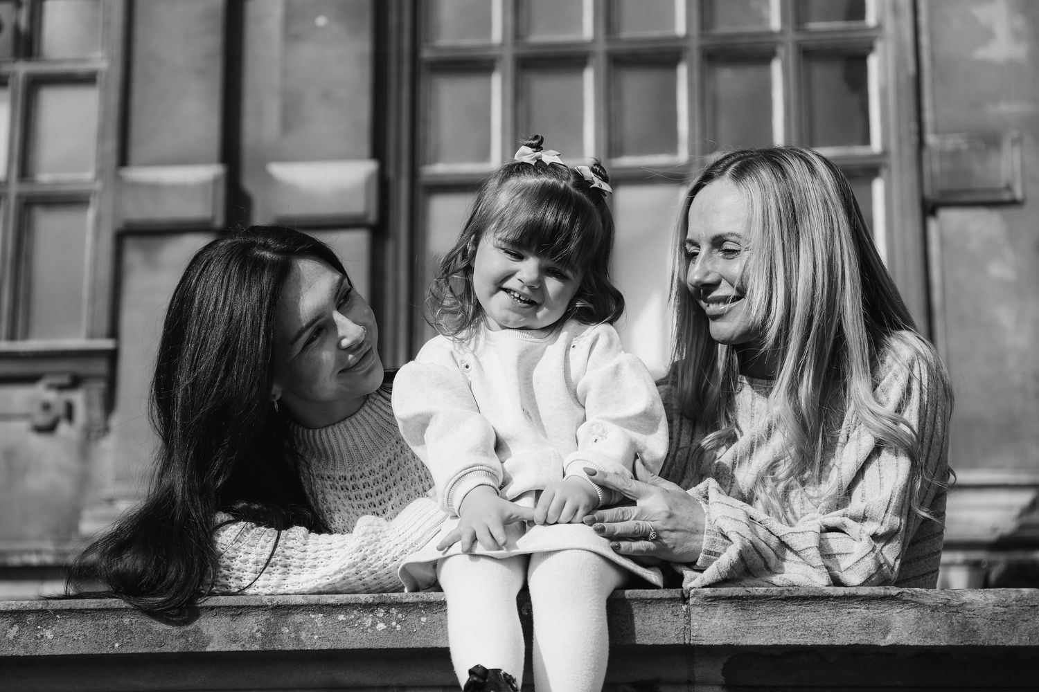 Black and white photo of three people sharing a happy moment during family outdoor shoot at Wollaton Hall, Nottingham