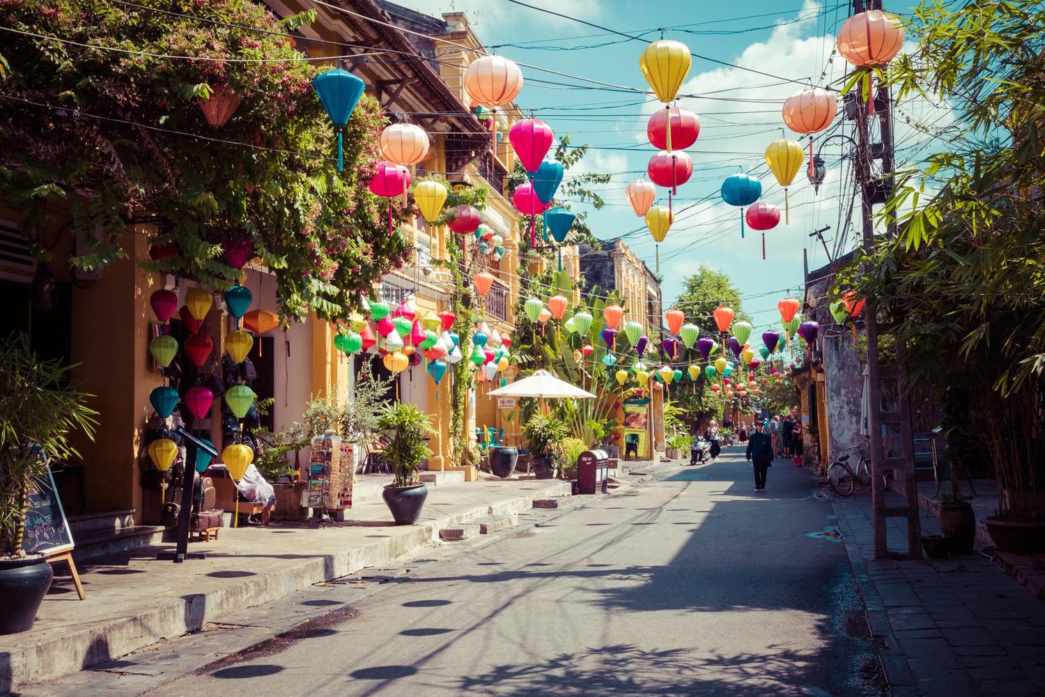 Colorful paper lanterns hanging over a charming street in Hoi An, Vietnam with traditional buildings and vibrant decor.
