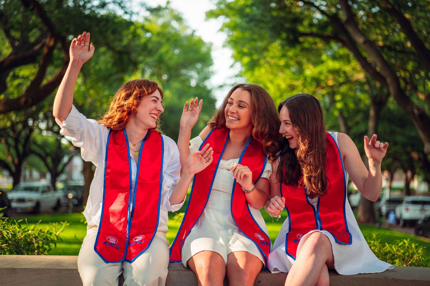A group wearing red vests celebrates joyfully outdoors in a park setting.