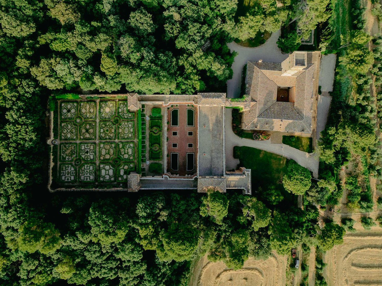 Aerial view of a historic mansion Villa Imperiale Pesaro surrounded by lush green trees with a formal garden layout.