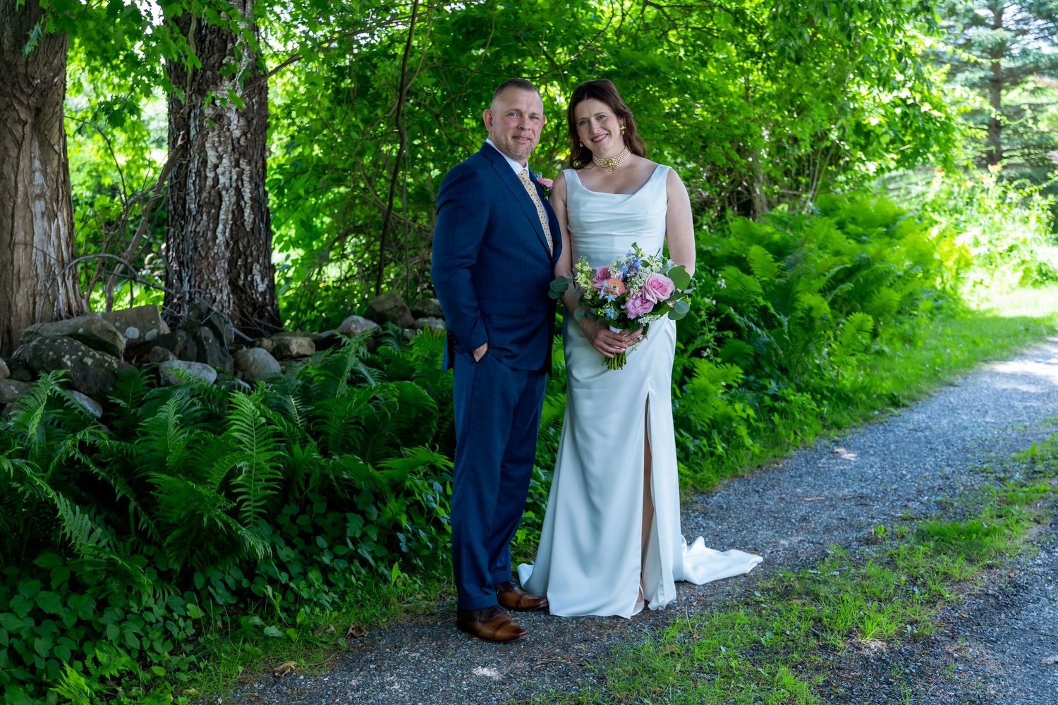 Wedding ceremony takes place under a rustic wooden pavilion with exposed beams and scenic view through archway in background.