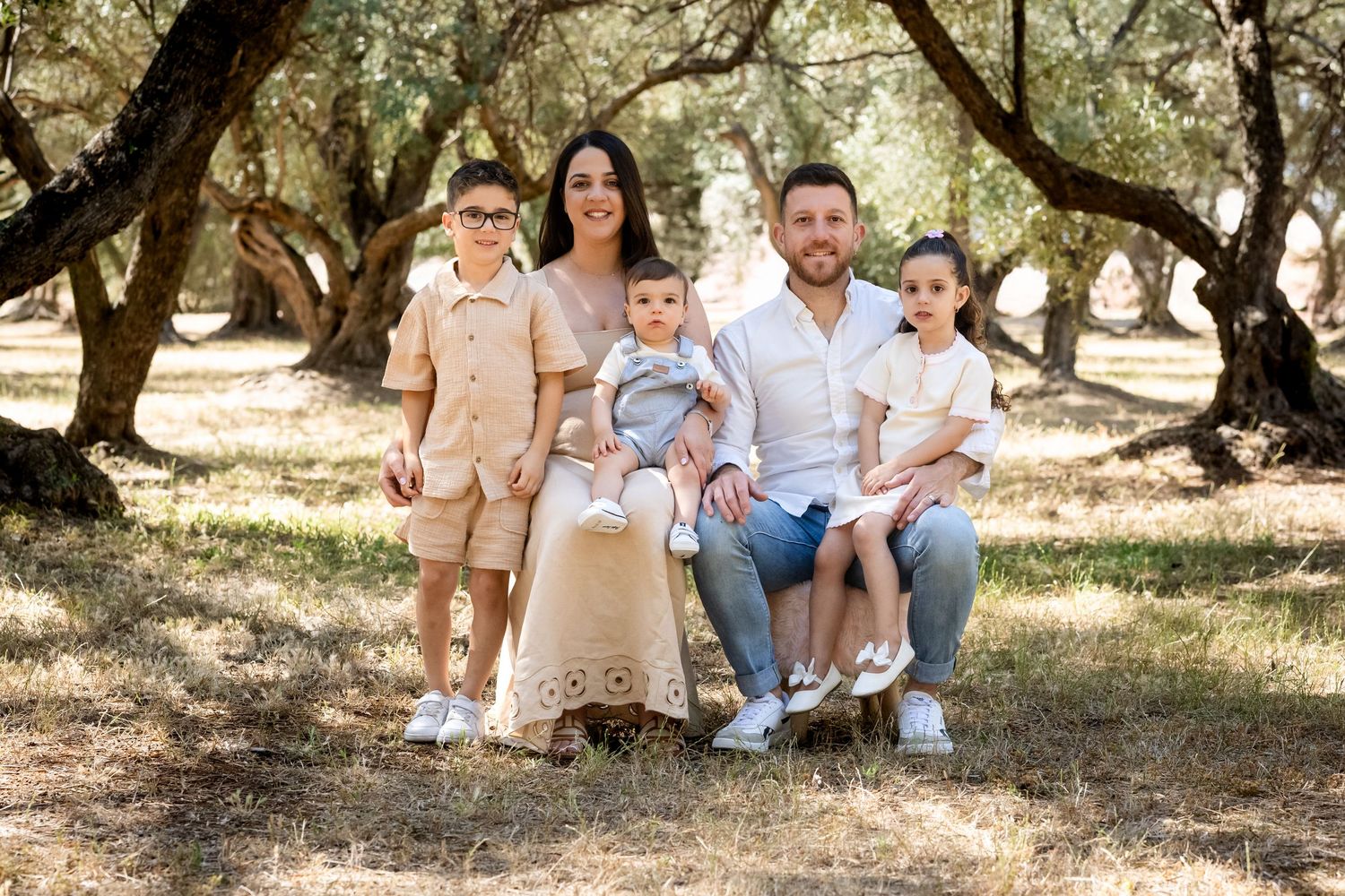 Family walking and playing together in a sun-dappled oak grove during golden hour photo session.