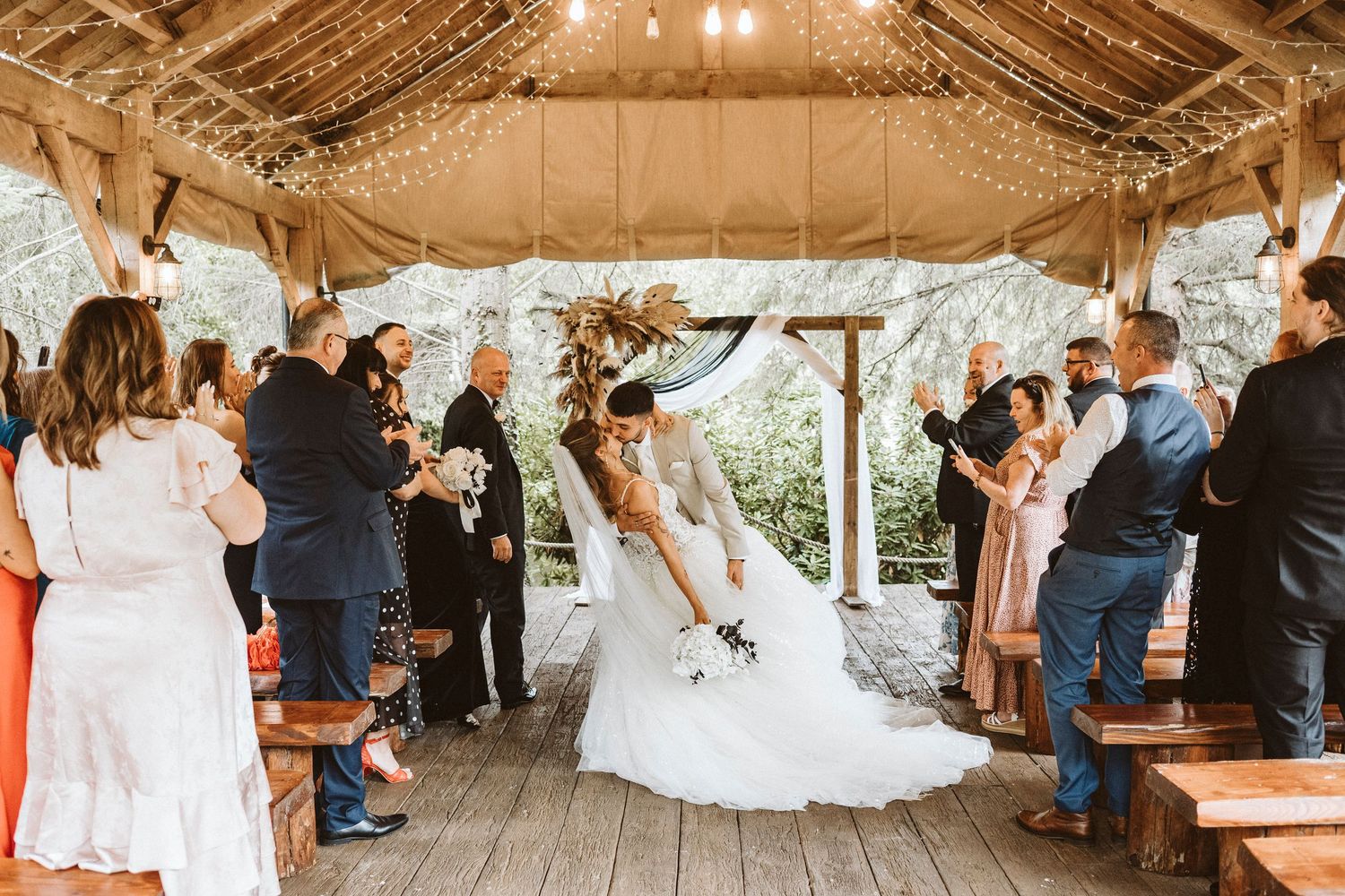 Rustic barn wedding venue decorated with string lights and filled with guests for a celebration ceremony.