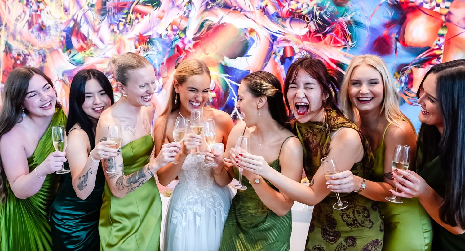 bridal party  in colorful dresses celebrate joyfully with drinks at Columbus museum of art