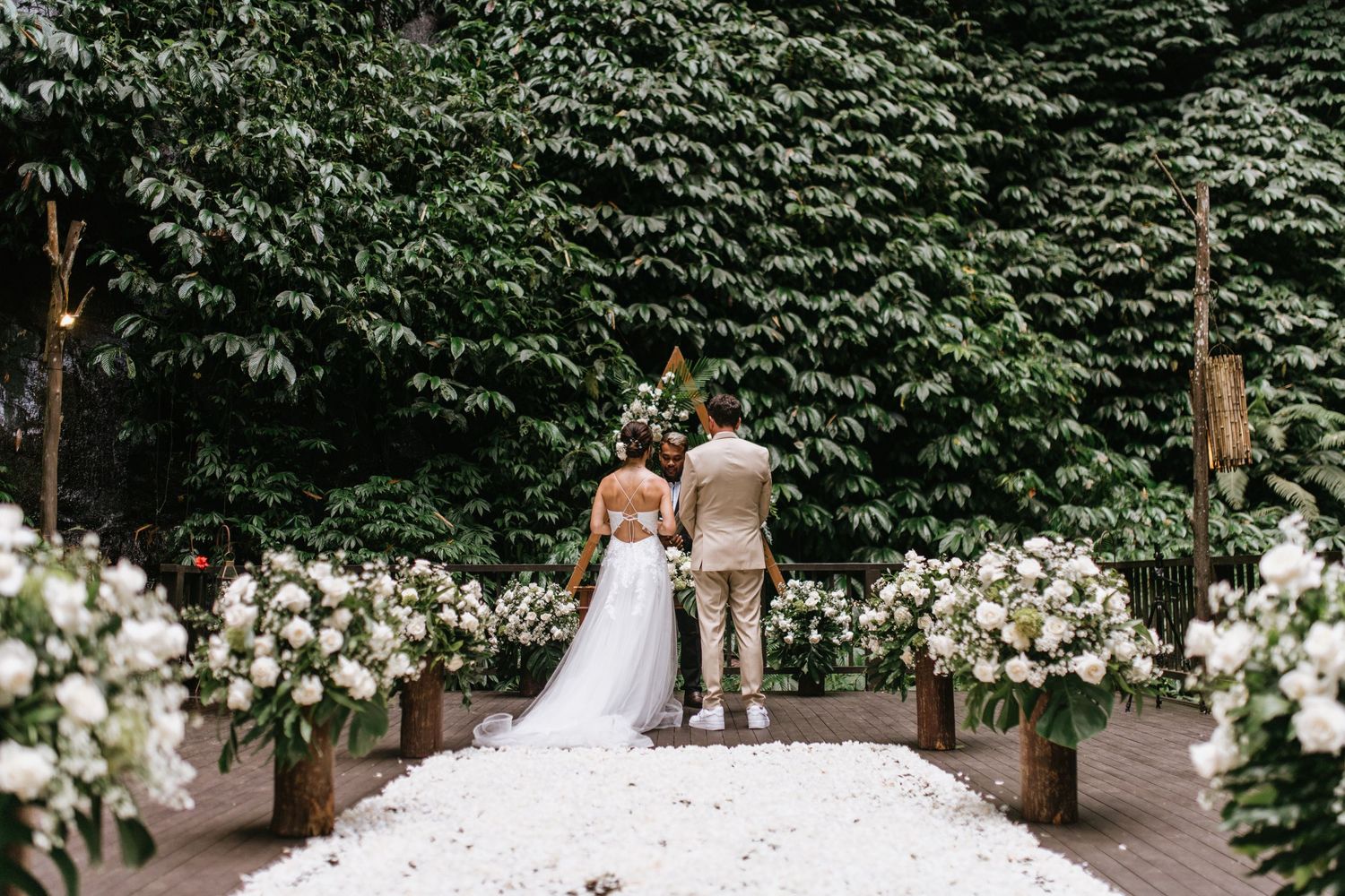 Elegant wedding ceremony space decorated with white floral arrangements and greenery backdrop.
