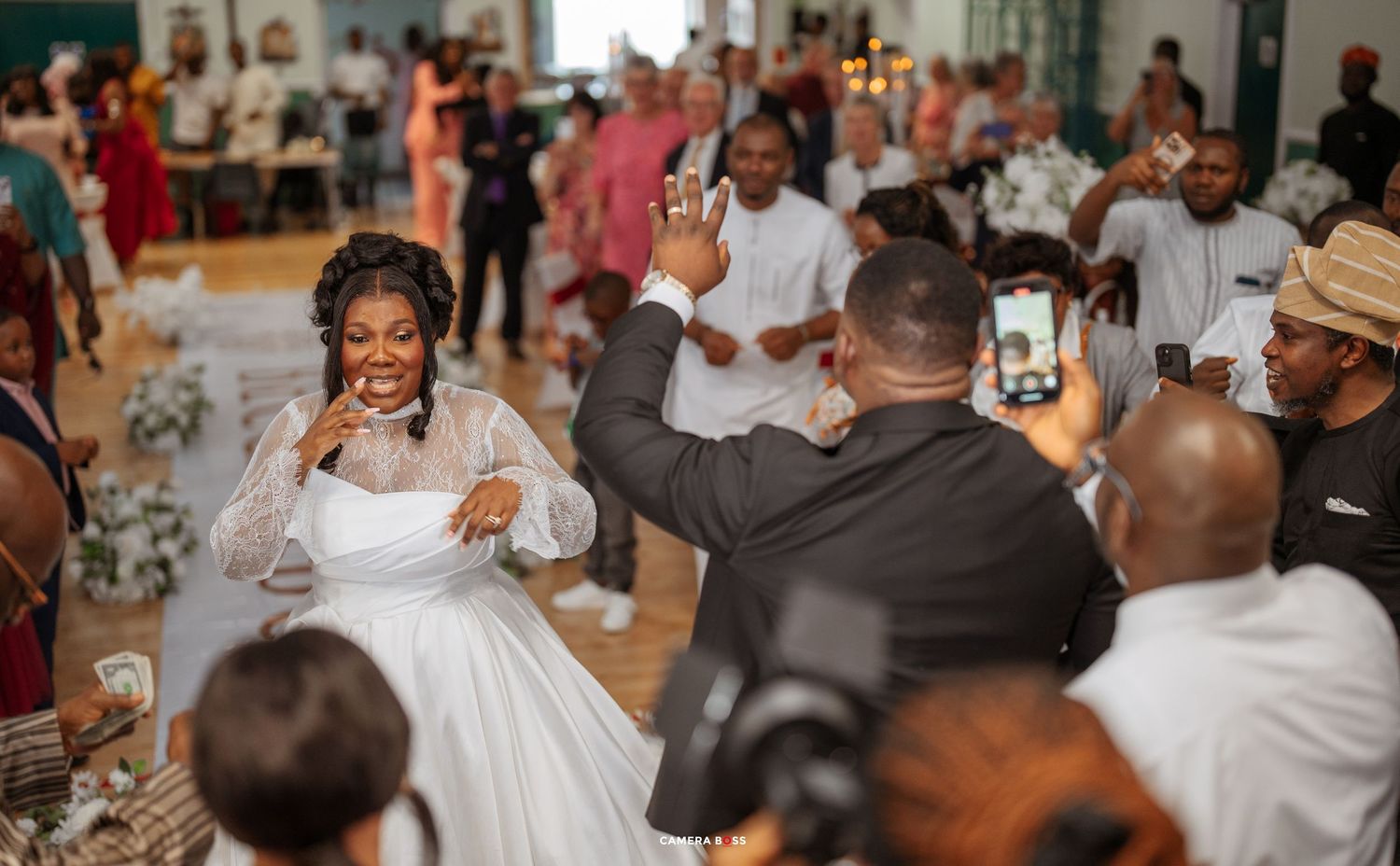 A celebration scene at a wedding reception with guests seated at decorated tables in an elegant venue.