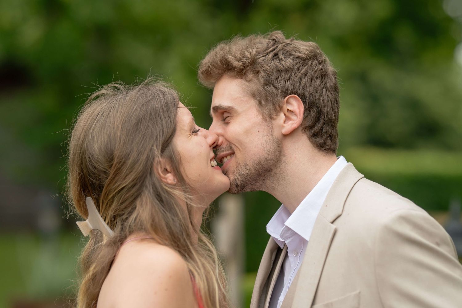 A romantic outdoor wedding moment between a couple sharing a tender kiss in a garden setting.