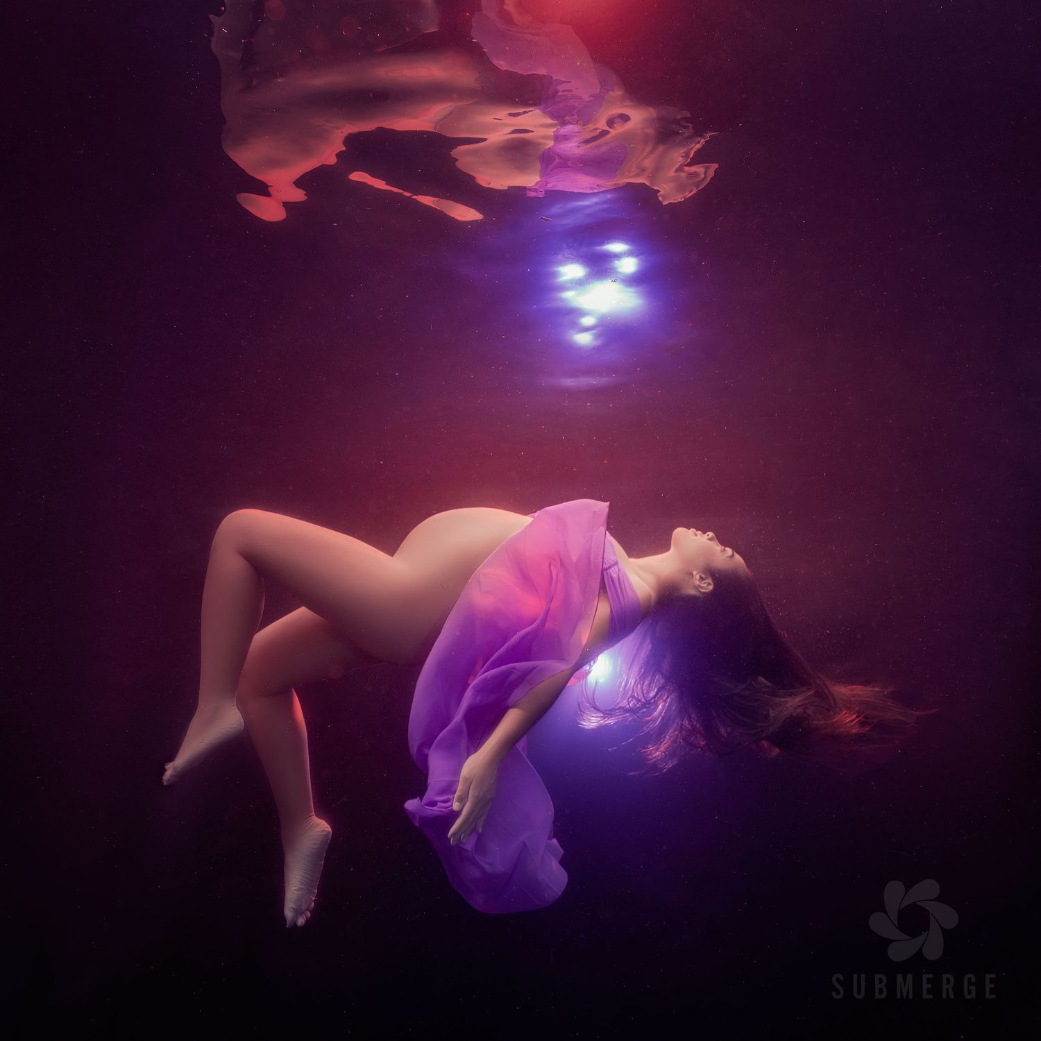 Ethereal underwater scene with floating figure in flowing purple dress illuminated by mystical blue lights from above.