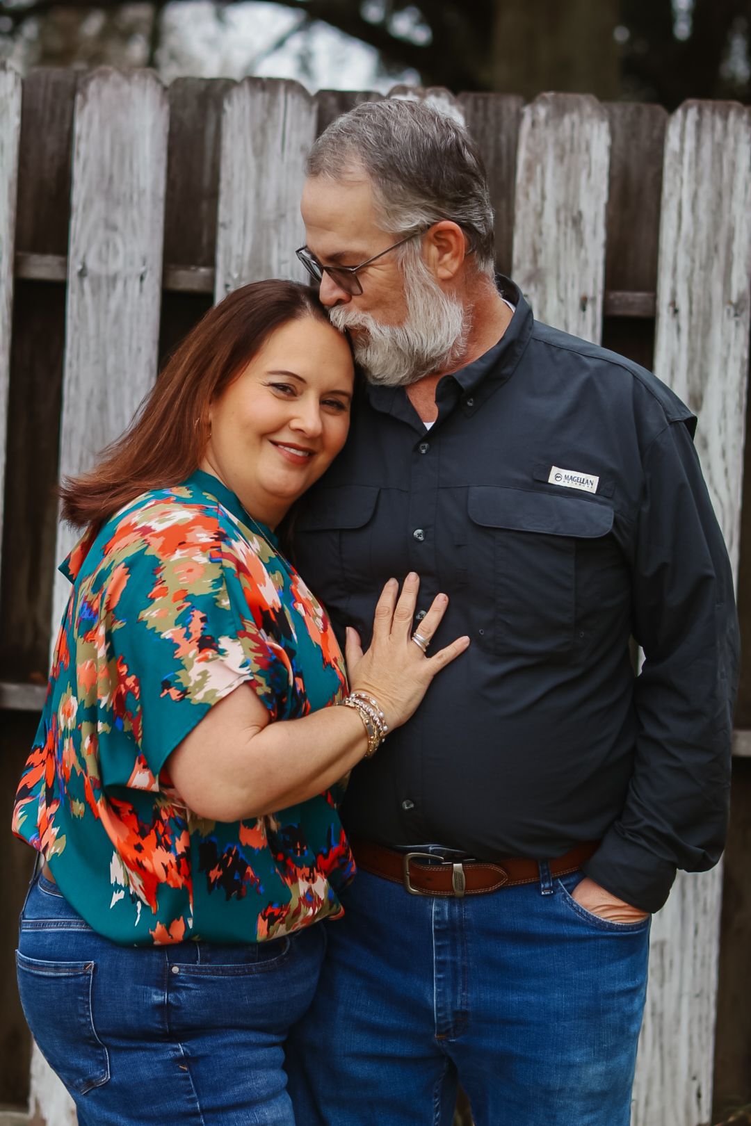 Couple sharing tender moment against rustic wooden fence.