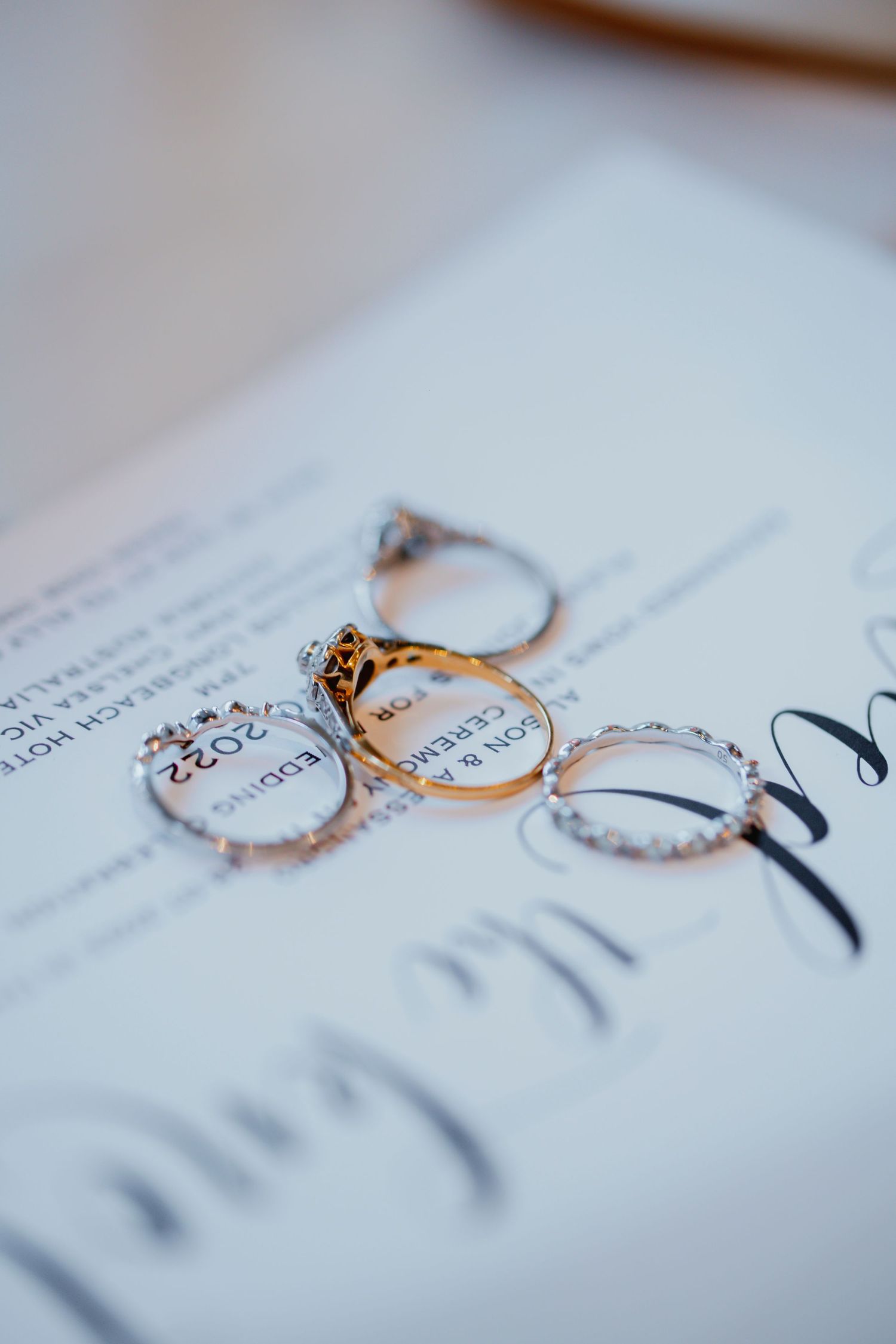 Close-up sequence of delicate engagement rings with diamonds casting shadows on white paper.