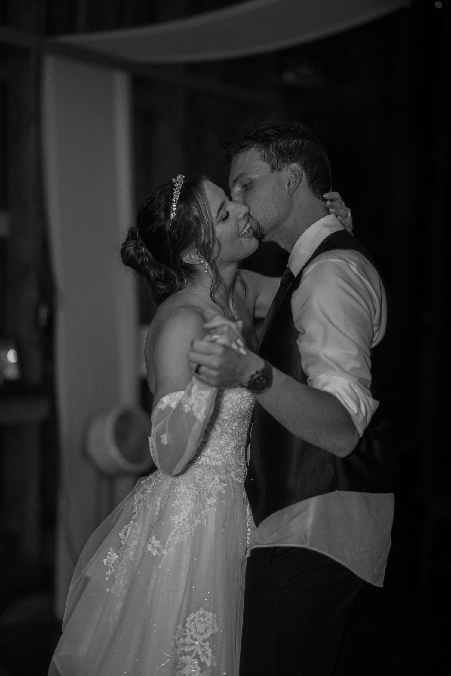 A romantic slow dance between partners at a wedding reception, captured in black and white photography.