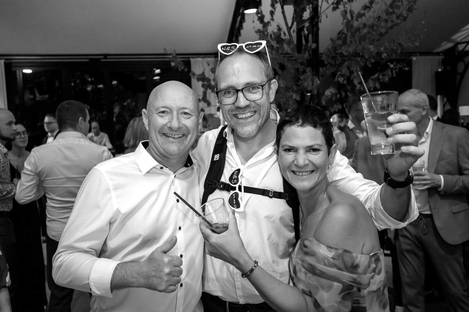 A festive group of guests at a celebration event socialize and share drinks together in professional attire.