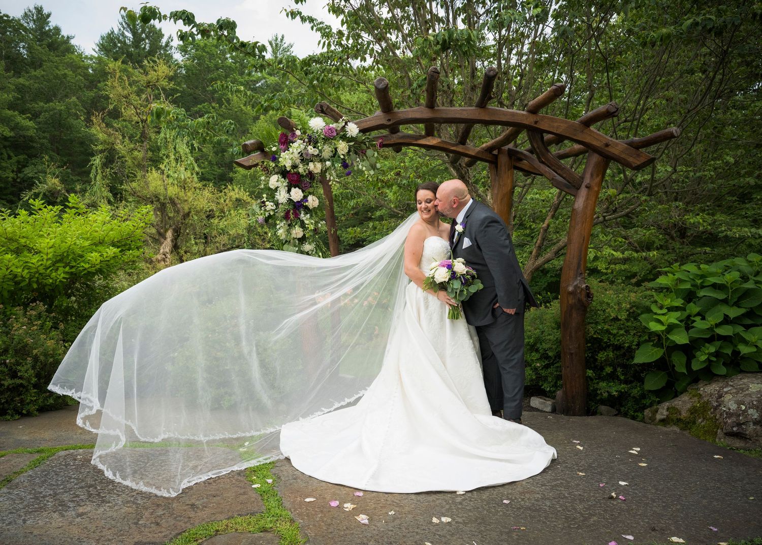 A romantic wedding sequence captured in a lush garden setting with flowing veil and wooden pergola creating a dreamy atmosphere.