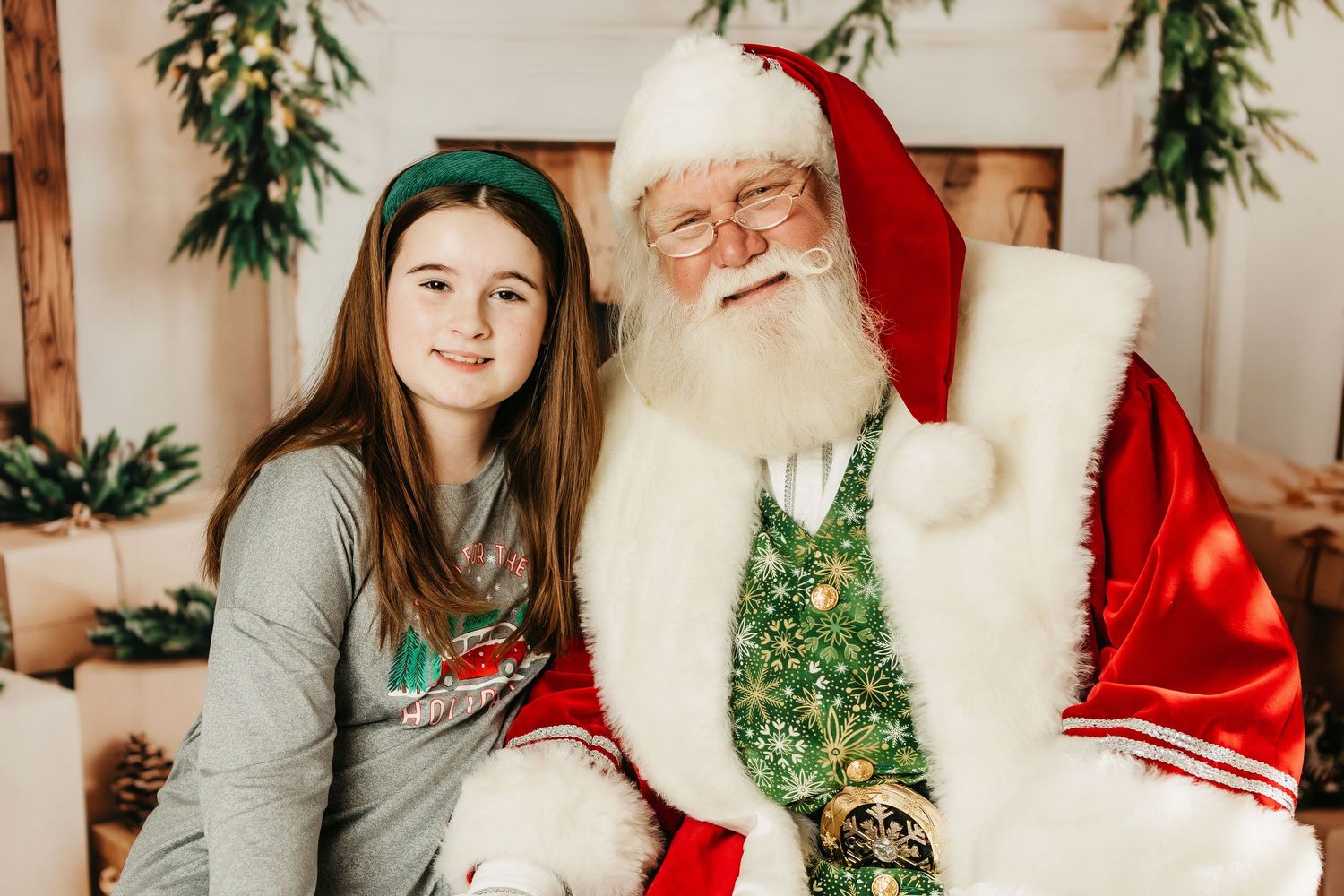 A festive holiday photo session with traditional Christmas decorations and evergreen garlands in a bright indoor setting.