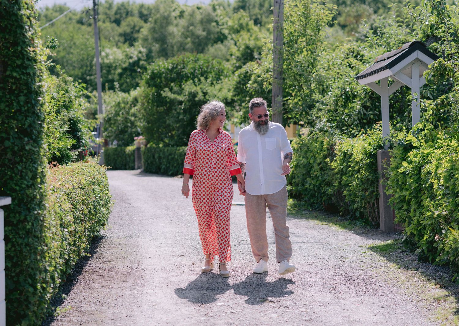 A couple shares a joyful moment outdoors, with the woman wearing a red polka dot top laughing as they embrace.