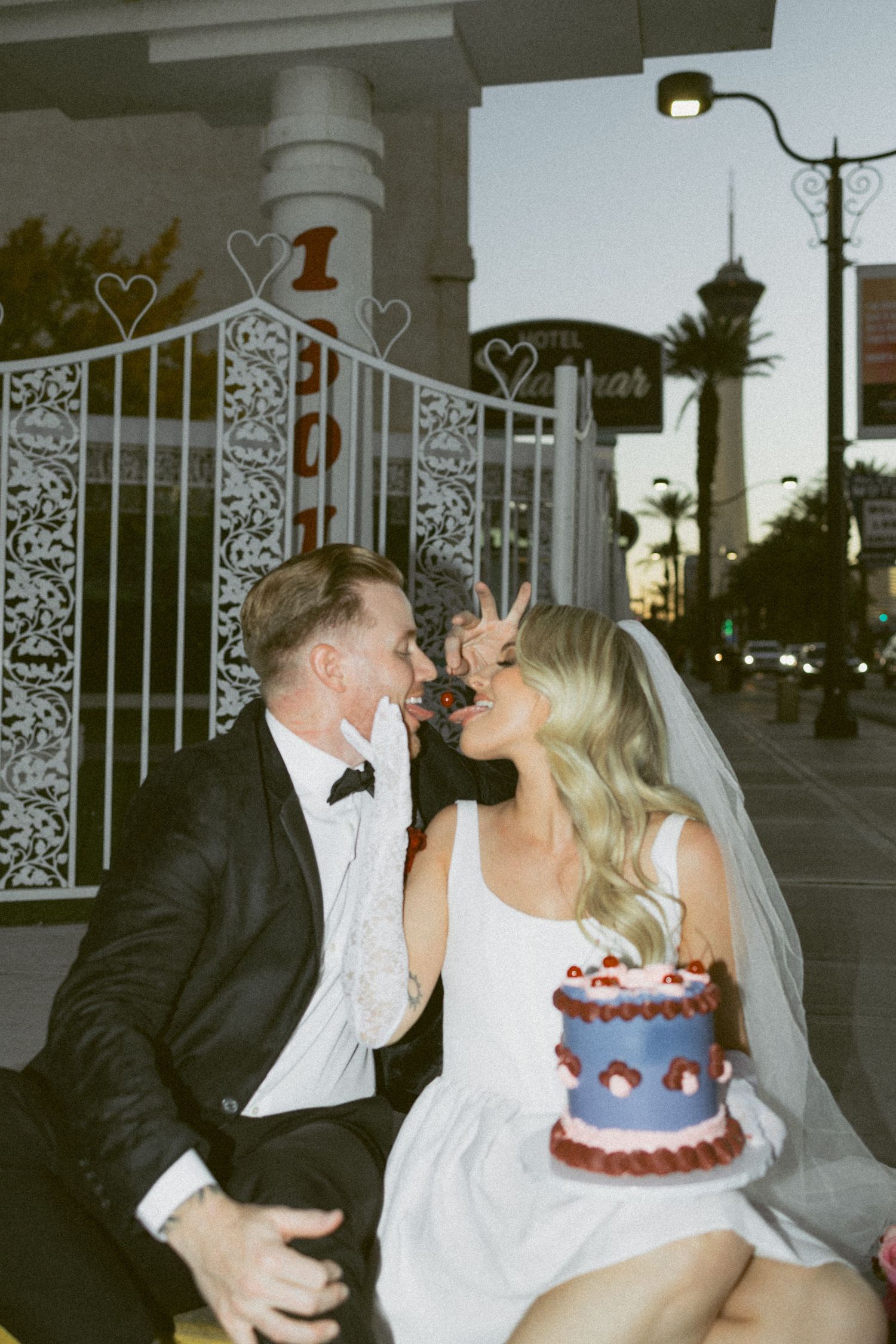 Wedding couple laughs while sharing their small purple wedding cake outside a chapel in Las Vegas.