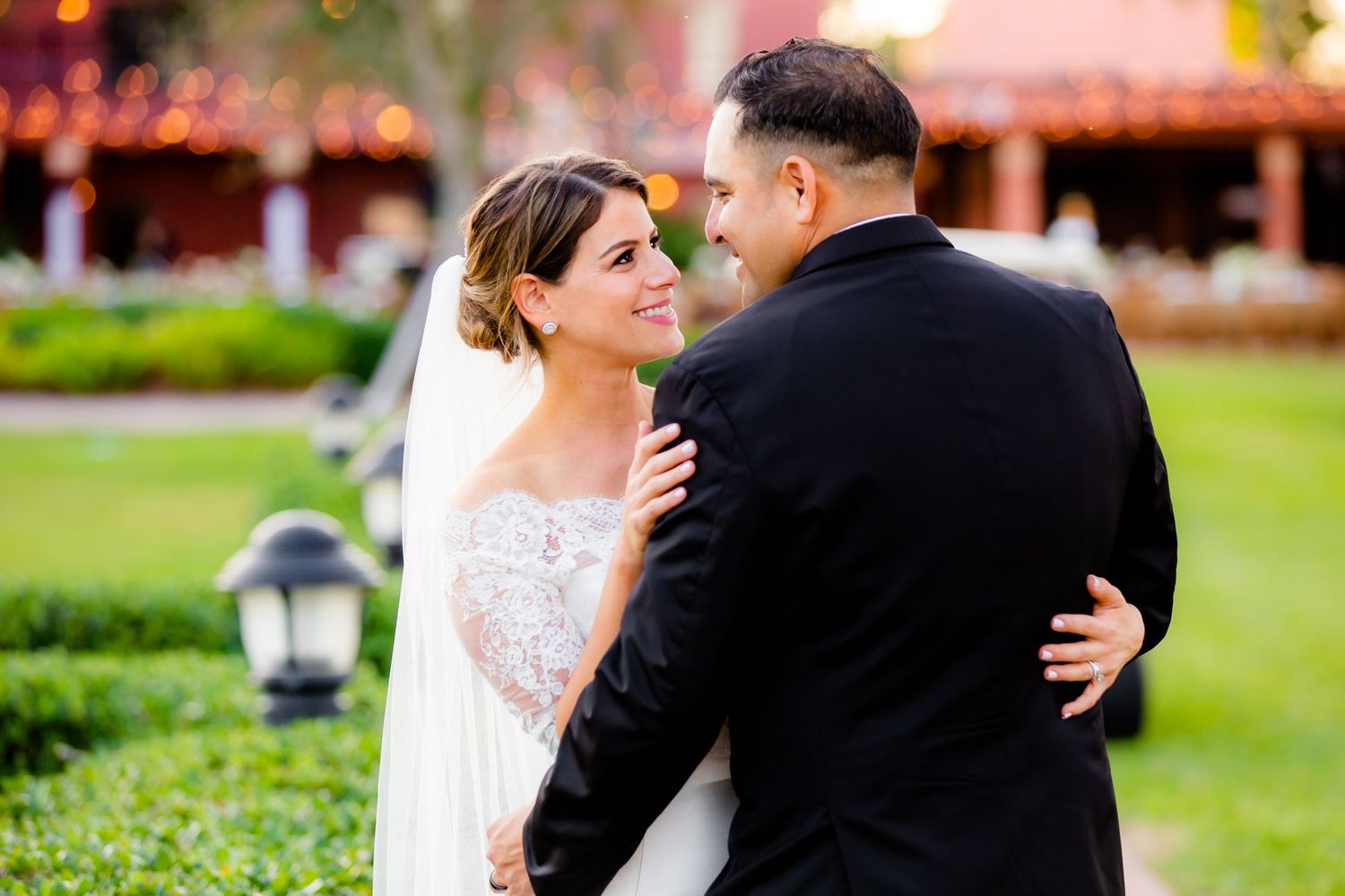 A couple embraces during their wedding celebration in a scenic outdoor setting.