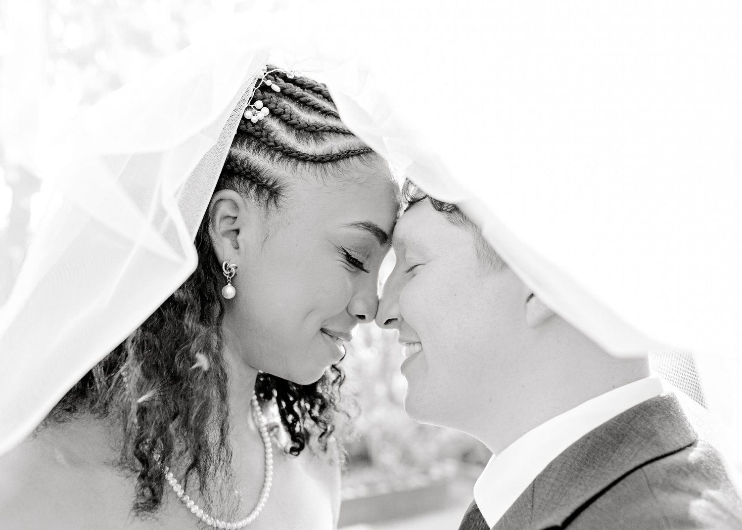 bride and groom forehead to forehead as veil is over their heads