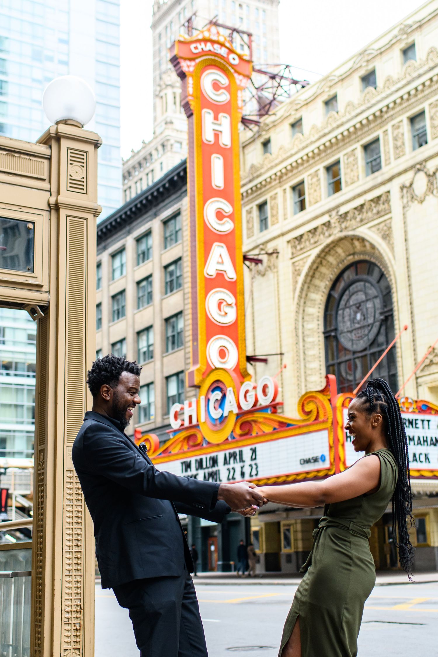 Couple poses playfully in front of iconic Chicago Theatre marquee sign.