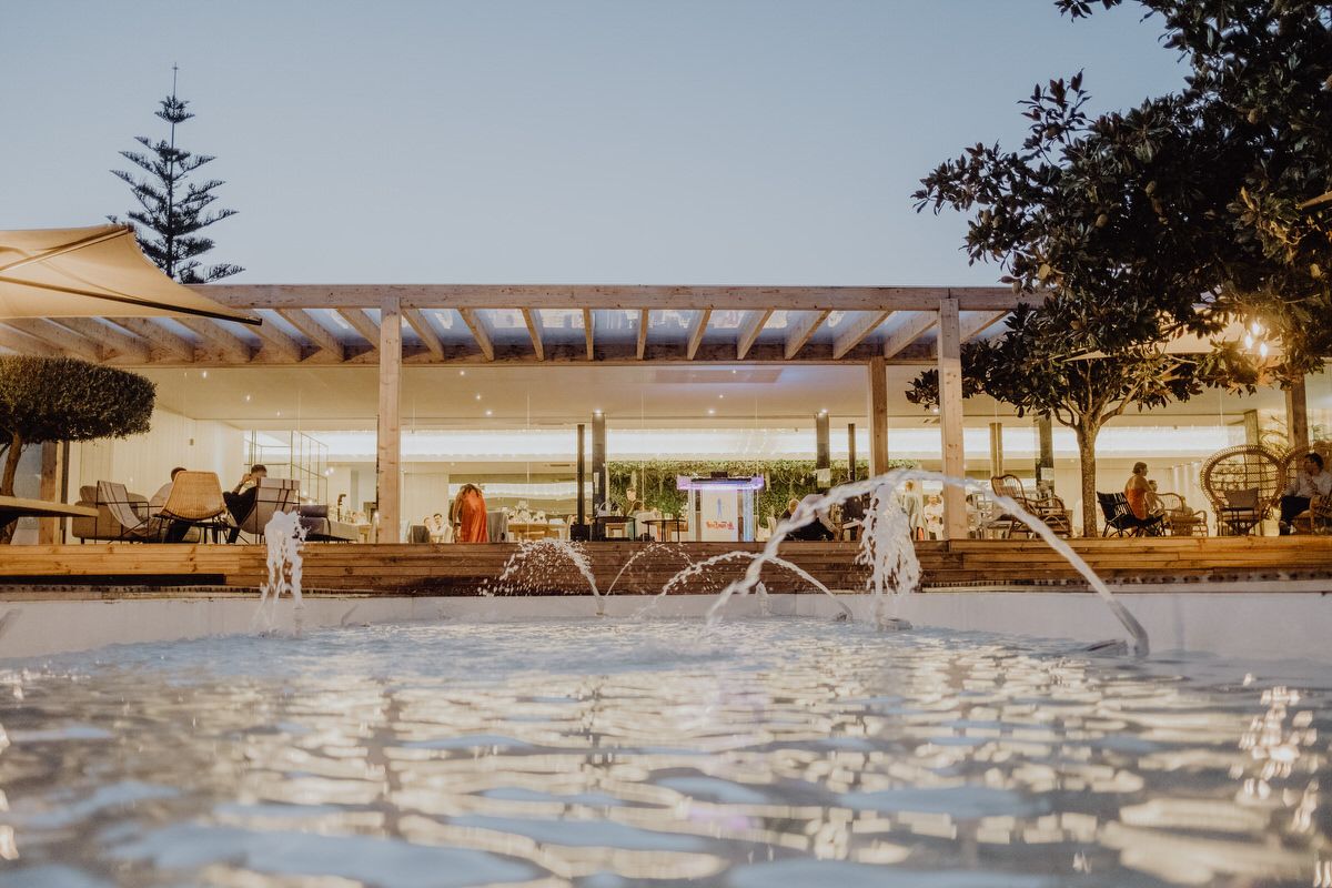Modern architectural venue with water features and fountains at sunset.