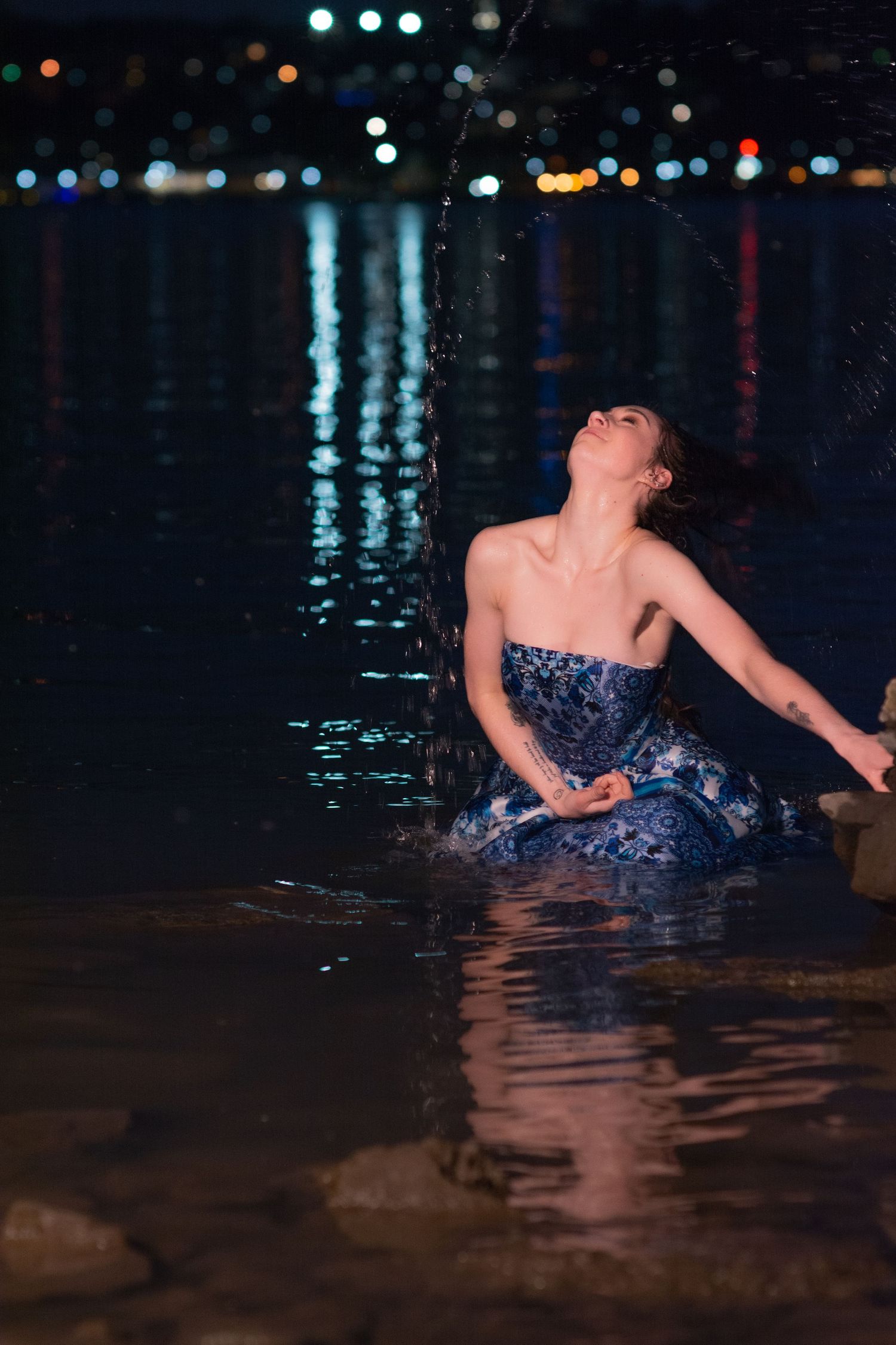 action freezing of girl whipping hair back with water drops from river