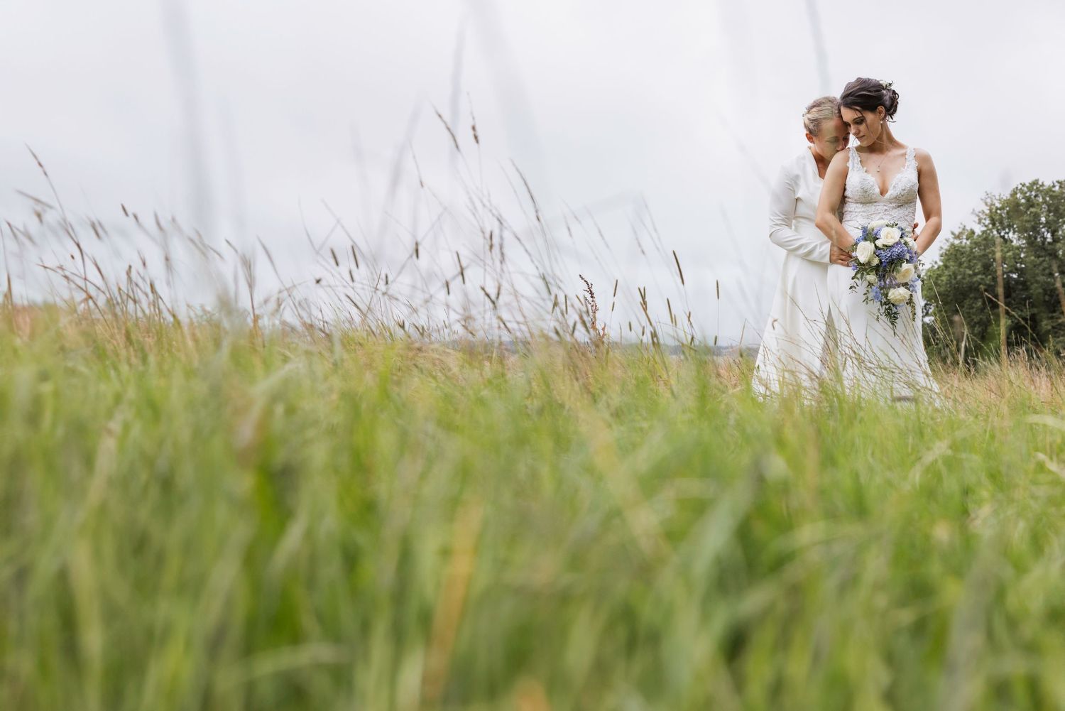 Dayna and Laura in a field sharing a tender moment at Swallows Oast after getting married.