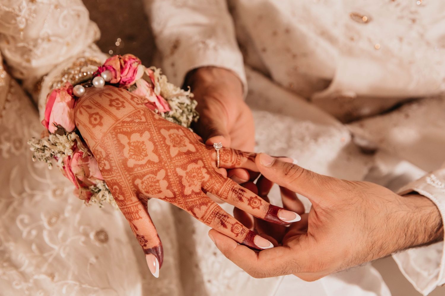 Close-up of intricate henna design on hands with floral decorations.